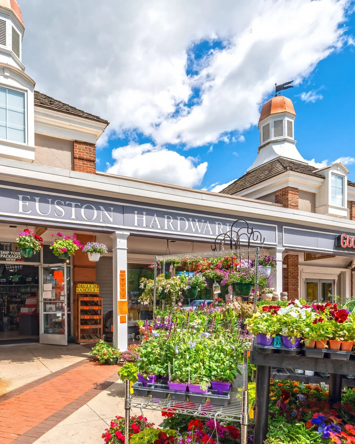 Charming storefront of Fusion Hardware with flower-lined windows and outdoor seating in the Prairie Village Shops district, Prairie Village, Kansas