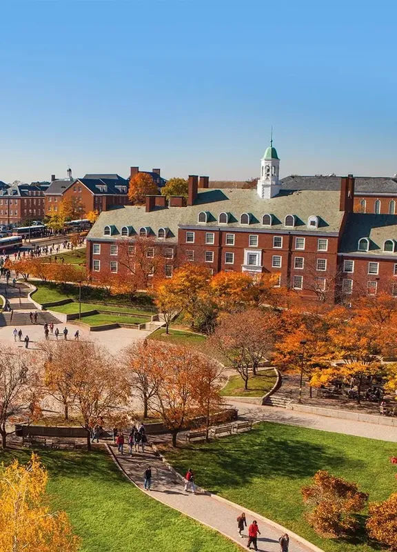 University of Maryland campus in College Park, MD, featuring historic red-brick academic buildings, tree-lined walkways, and students gathering across the landscaped campus during autumn.