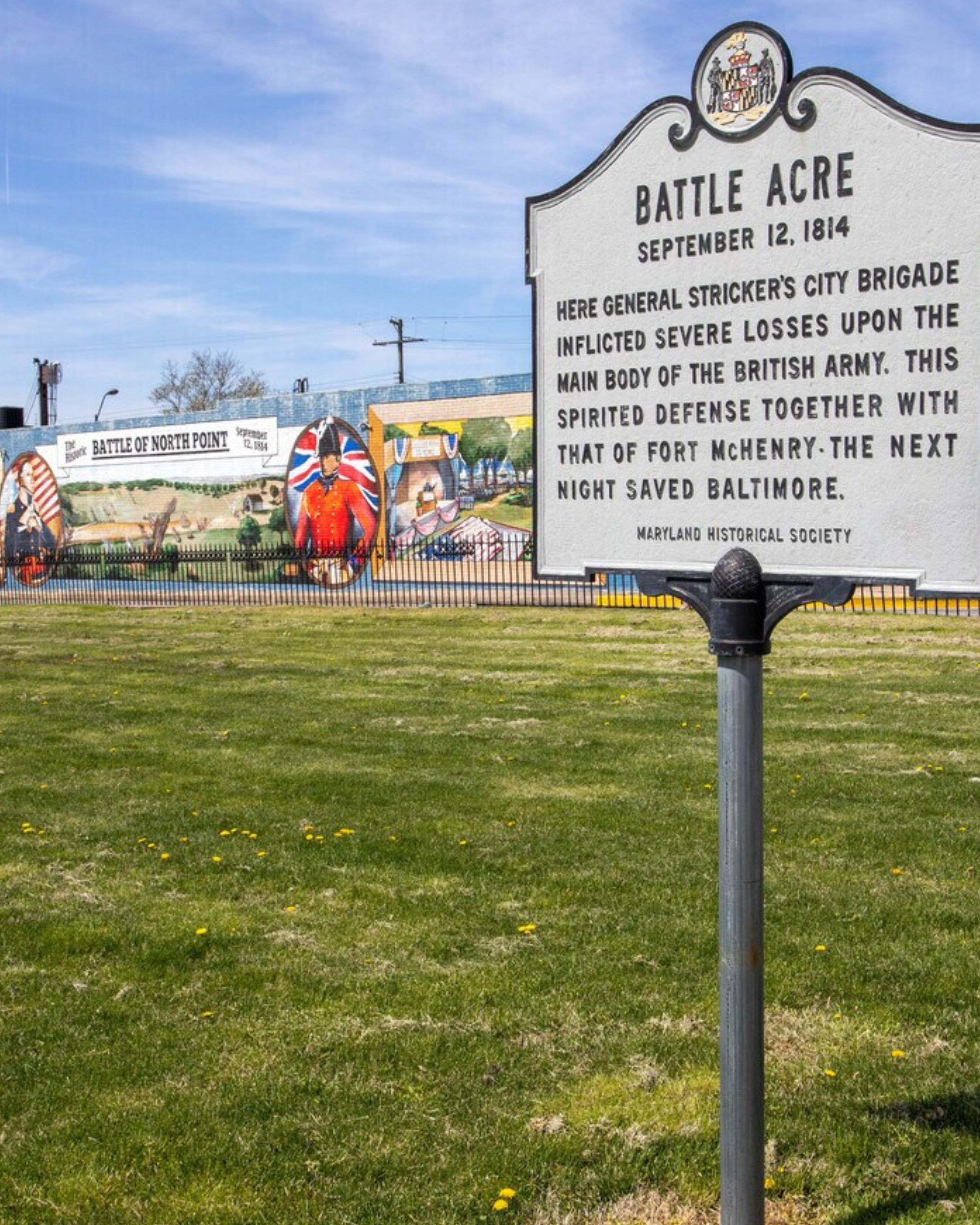 Historic Battle Acre marker in Dundalk, Maryland, commemorating the Battle of North Point with colorful murals and local history in the background.