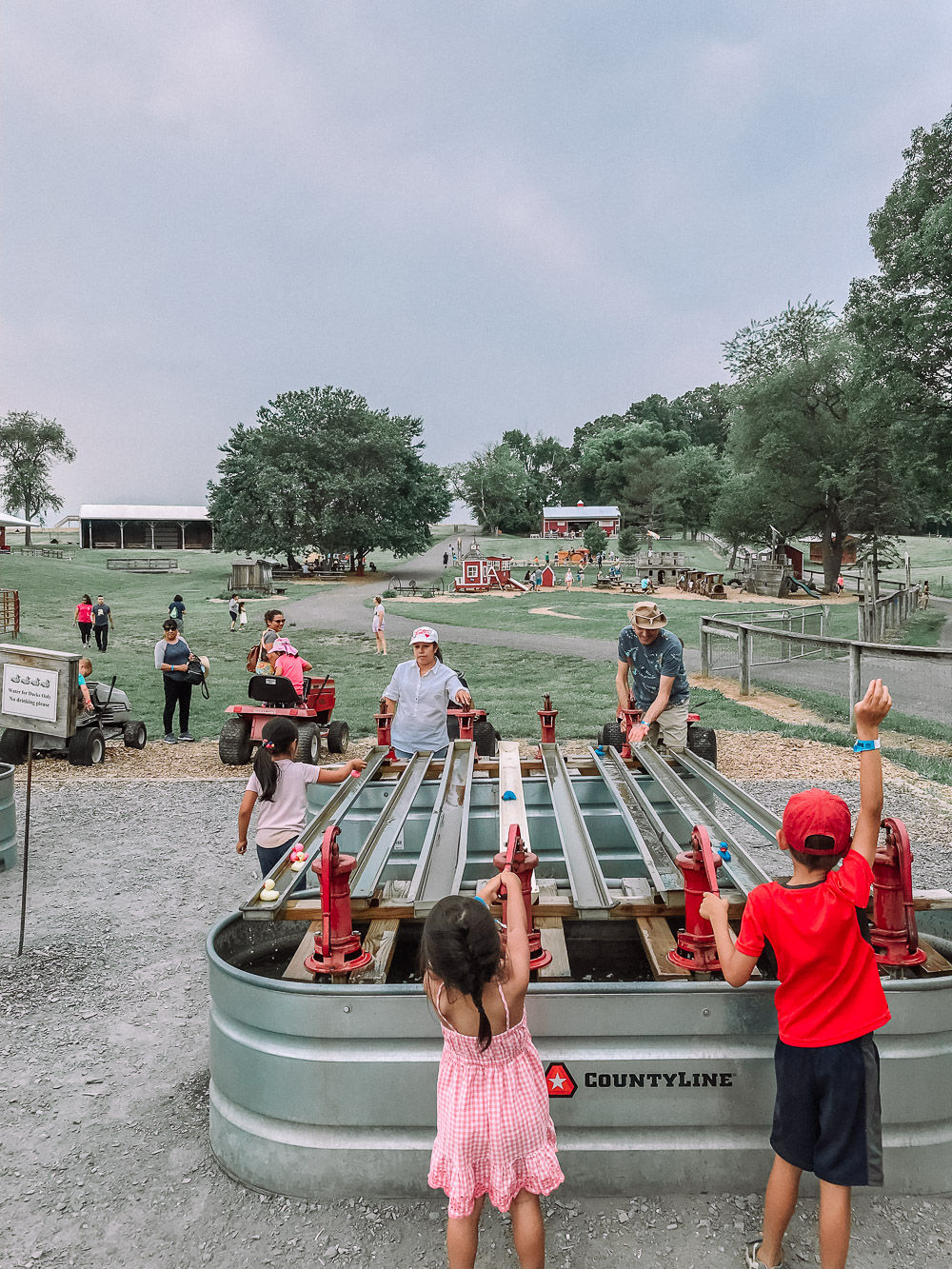 Families enjoying outdoor activities at Butler's Orchard in Germantown, Maryland, featuring children playing at interactive farm attractions in a scenic countryside setting.