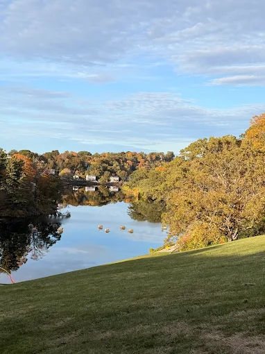 Scenic view of the Nashua River in Clinton, MA featuring calm water reflections, tree-lined banks, and surrounding greenery during early autumn
