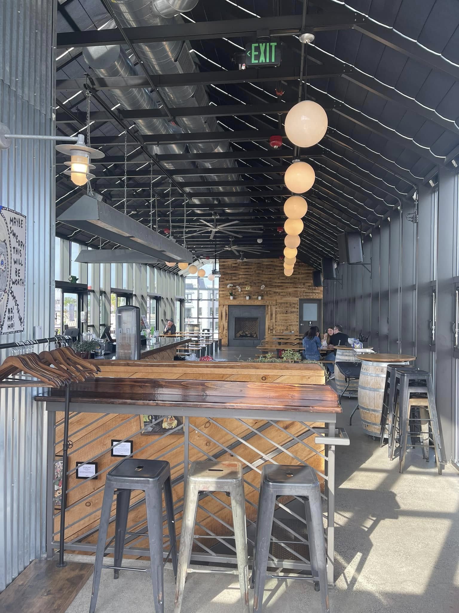 Interior of Dorchester Brewing Company in Dorchester, Massachusetts, featuring a modern industrial taproom with wooden furnishings, high ceilings, and a spacious gathering area for guests.