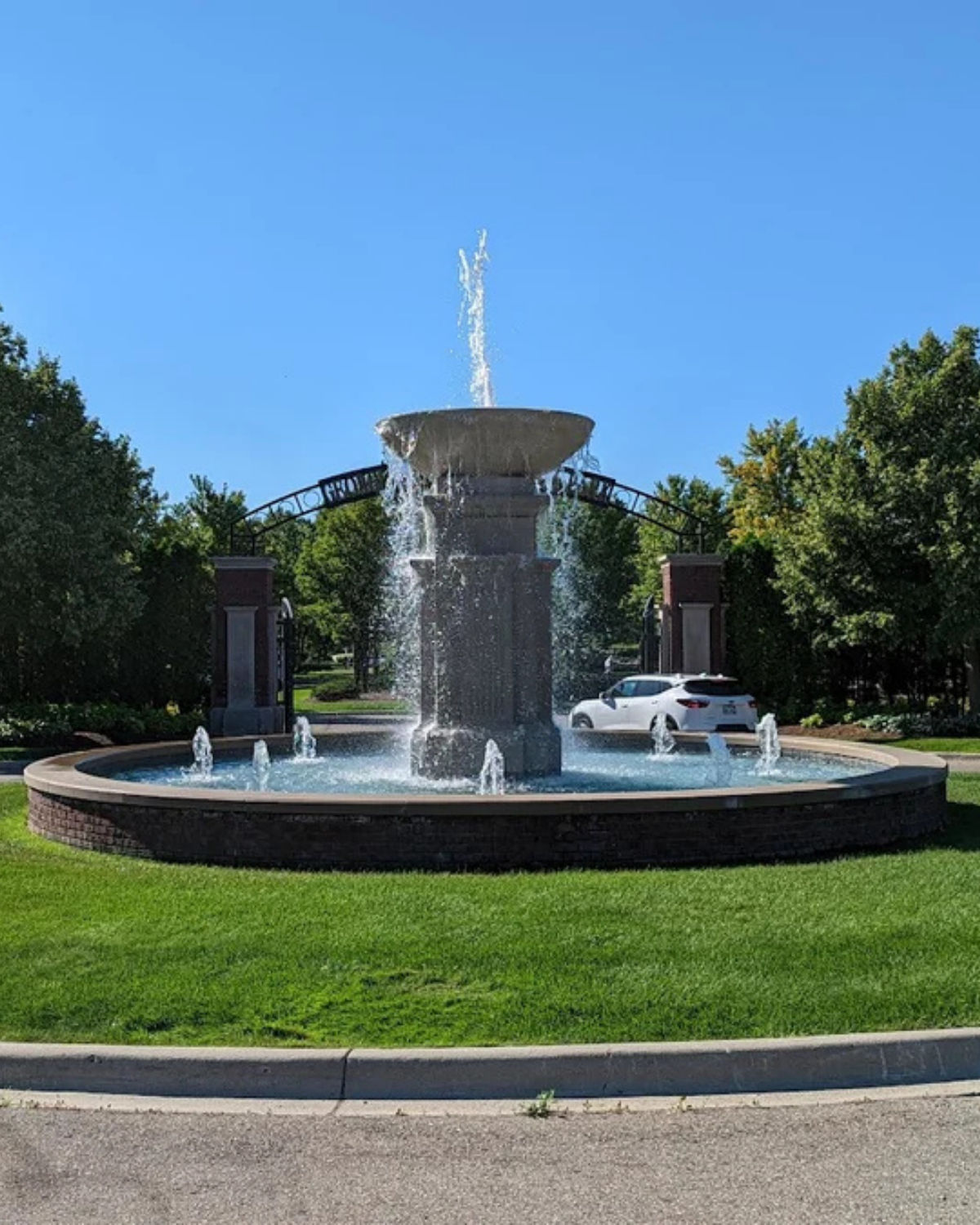 View of the signature round fountain at the entrance to George George Memorial Park in Clinton Township, Michigan, with water spraying into its circular pool
