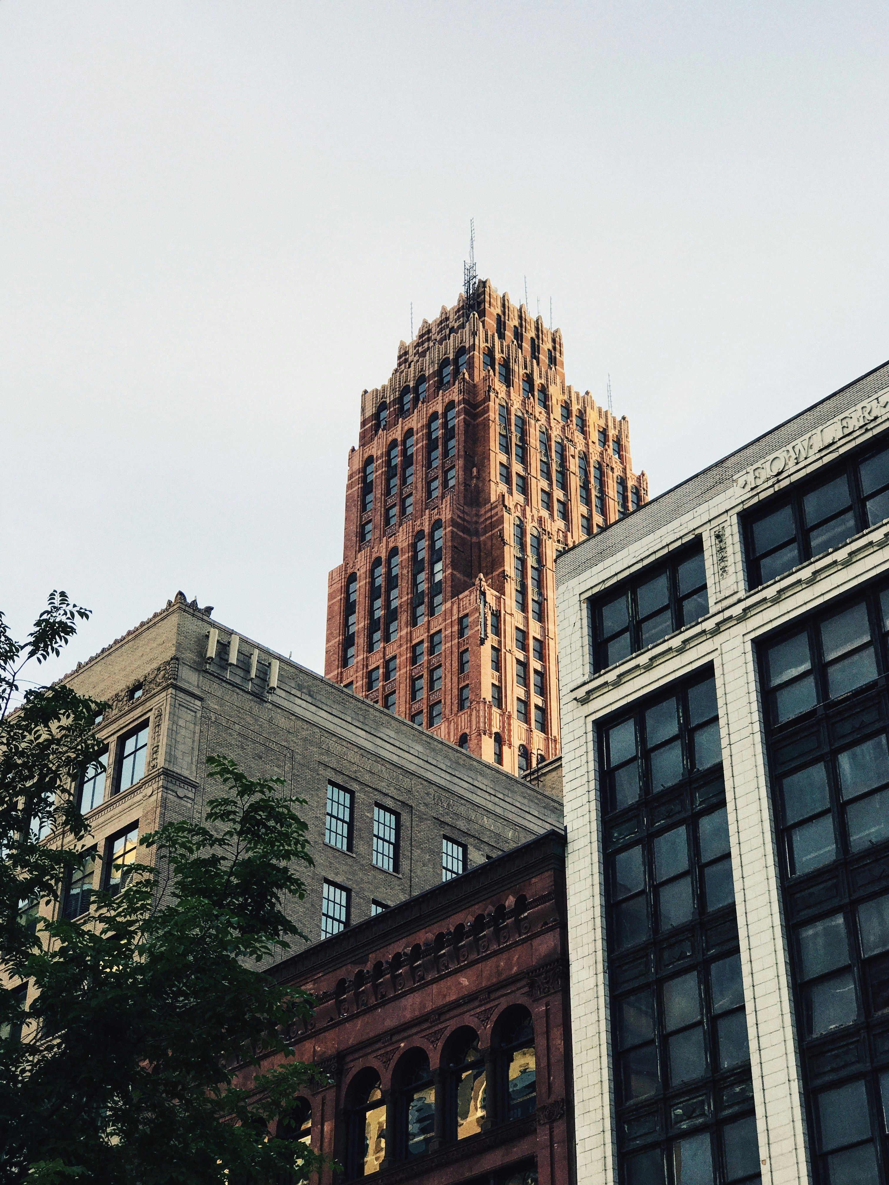 Close-up architectural view of a classic Detroit brick high-rise building with ornate Art Deco detailing against a blue sky