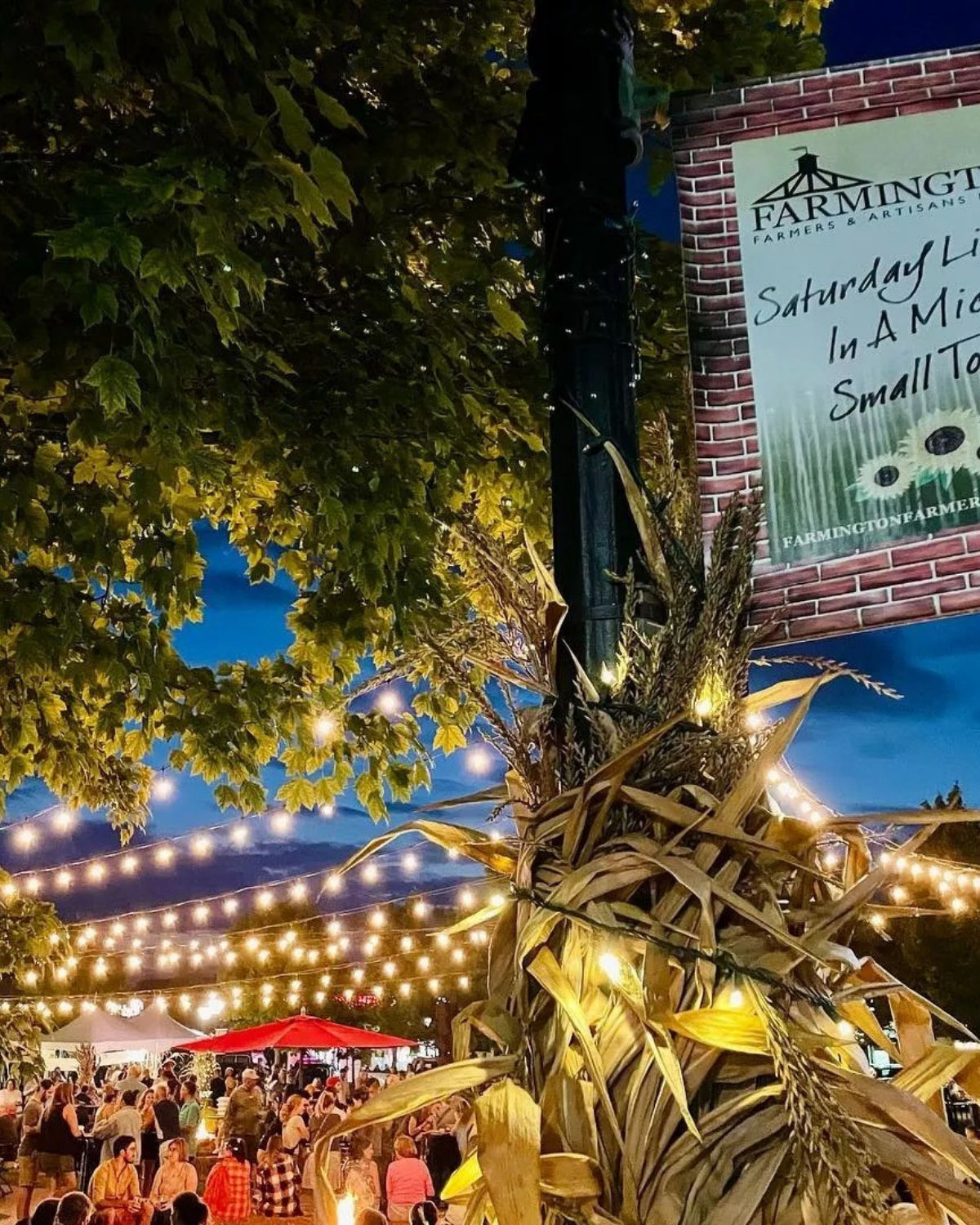 Festive string lights and colorful signage along a lively downtown Farmington, Michigan street during a community evening event