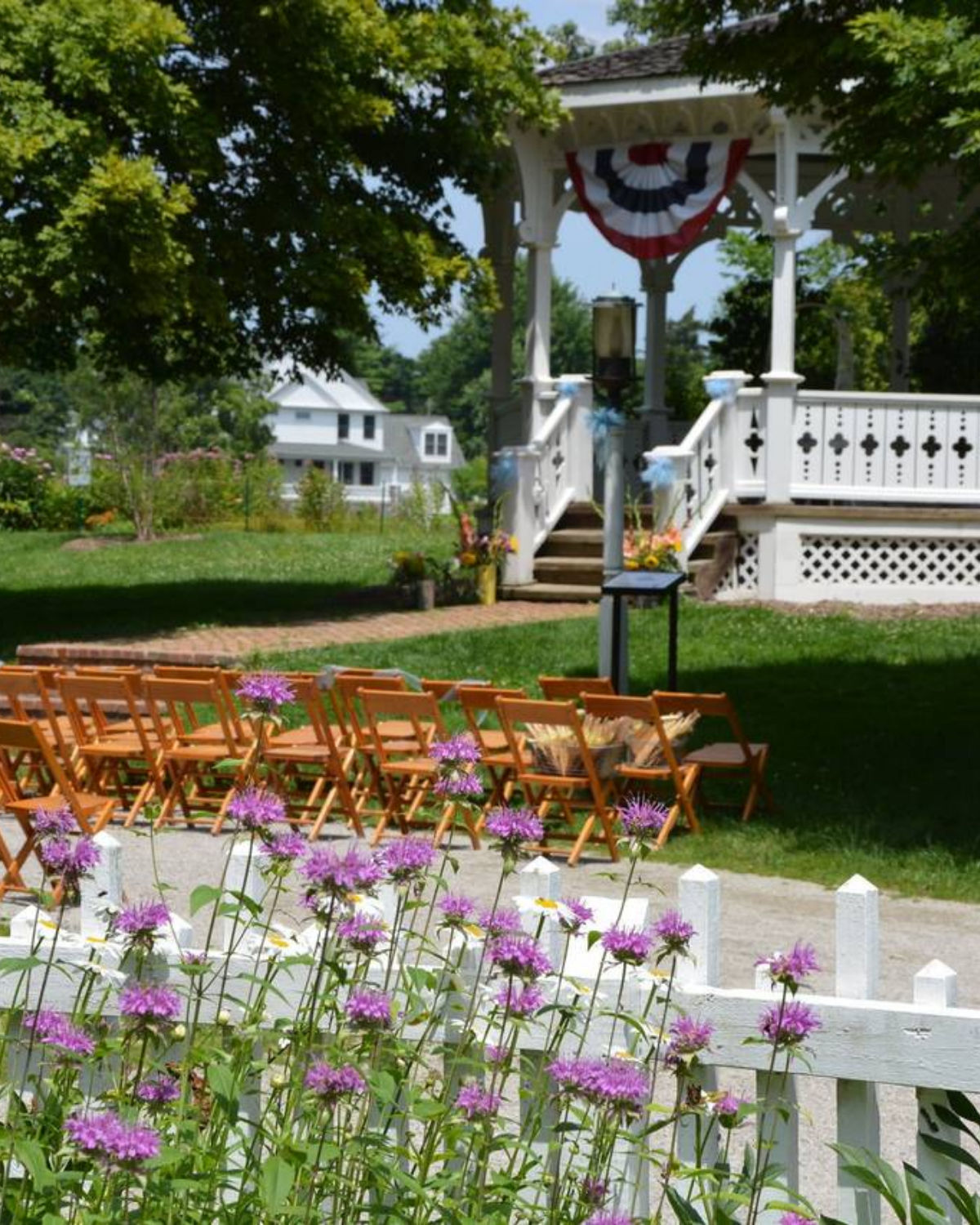 Elegant outdoor wedding ceremony setup with wooden chairs and floral arrangements on the grounds of Mill Race Historical Village in Northville, Michigan