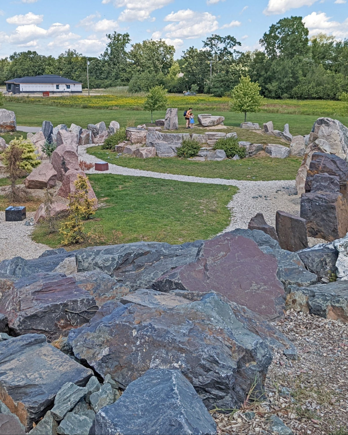 Rocky trail winding through a nature preserve with large boulders and lush green vegetation at Carpenter Lake Nature Preserve in Southfield, Michigan