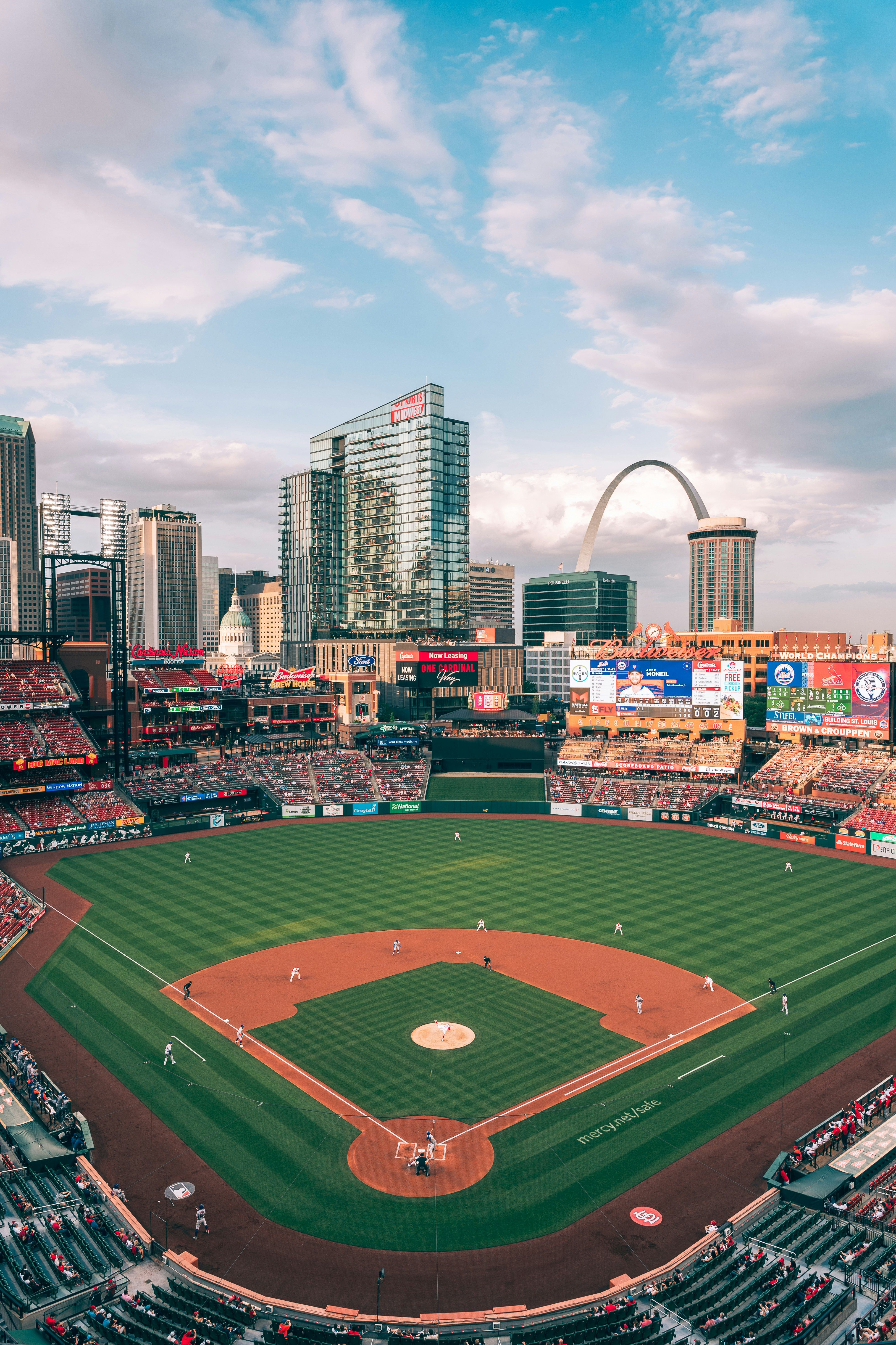 Aerial view of Busch Stadium packed with Cardinals fans during a game with the Gateway Arch and the St. Louis, Missouri skyline visible beyond the outfield