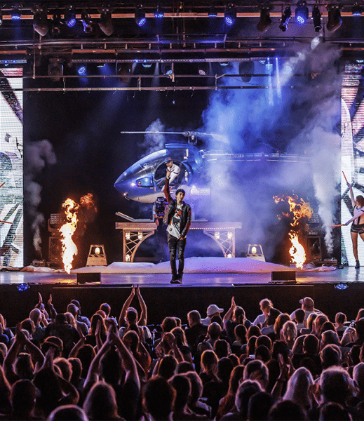 Live concert performance near Cedar Knolls, New Jersey, featuring a large crowd, dramatic stage lighting, pyrotechnics, and a helicopter incorporated into the stage production.