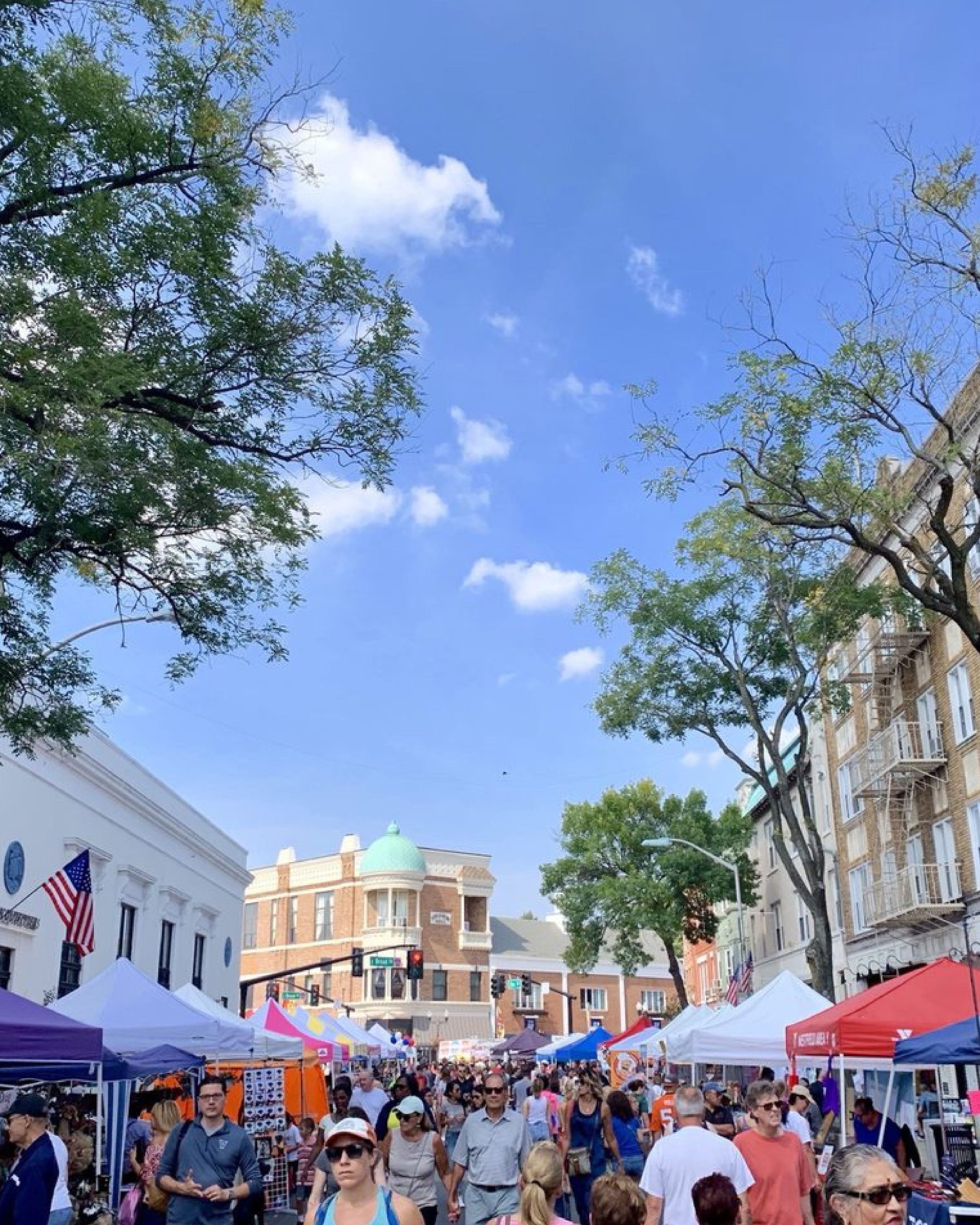 Crowded outdoor street fair in Clark, New Jersey, featuring local vendors, colorful tents, and community members enjoying a lively downtown event.