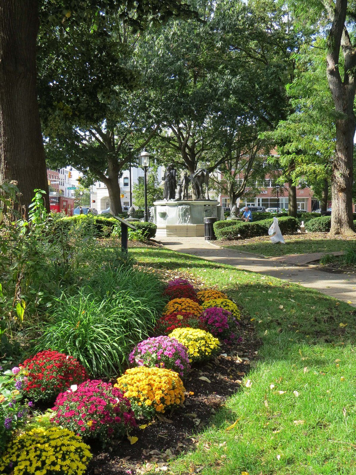 Morristown Green in downtown Morristown, New Jersey, showcasing vibrant seasonal flower beds, landscaped greenery, and shaded walking paths surrounding a historic central fountain, with charming urban architecture and a lively, walkable city atmosphere in the background—highlighting local culture, outdoor recreation, and one of North Jersey’s most popular community gathering spaces.