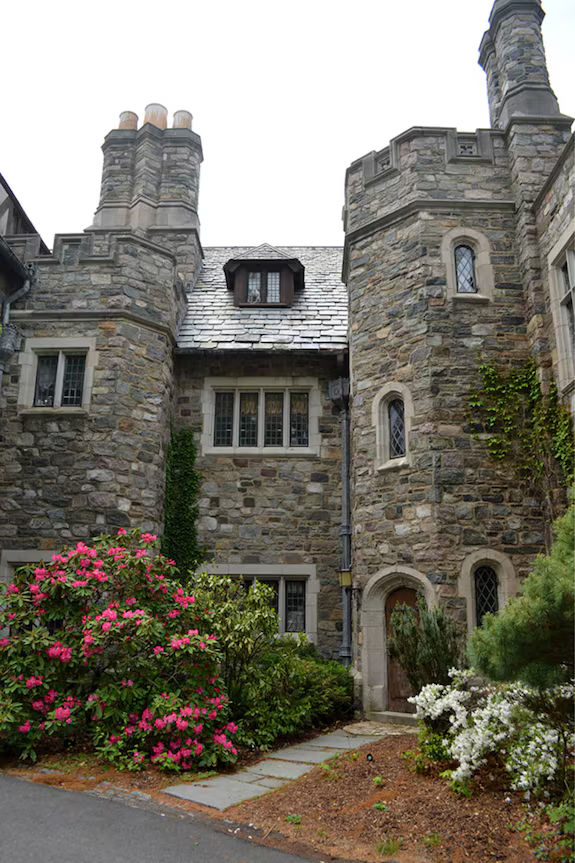 Historic stone exterior of Skylands Manor at the New Jersey Botanical Garden in Ringwood State Park, featuring Tudor Revival architecture, stone towers, leaded windows, a slate roof, ivy, and landscaped gardens. Skylands Manor was designed by John Russell Pope in the 1920s and sits within the New Jersey Botanical Garden.