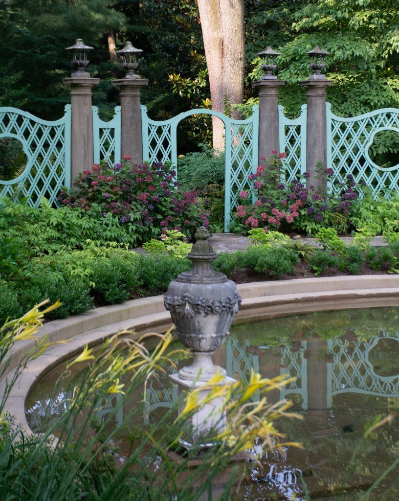 The formal gardens at the Greenwood Gardens estate in Short Hills, New Jersey, featuring ornamental fountains, decorative fencing, and landscaped greenery.