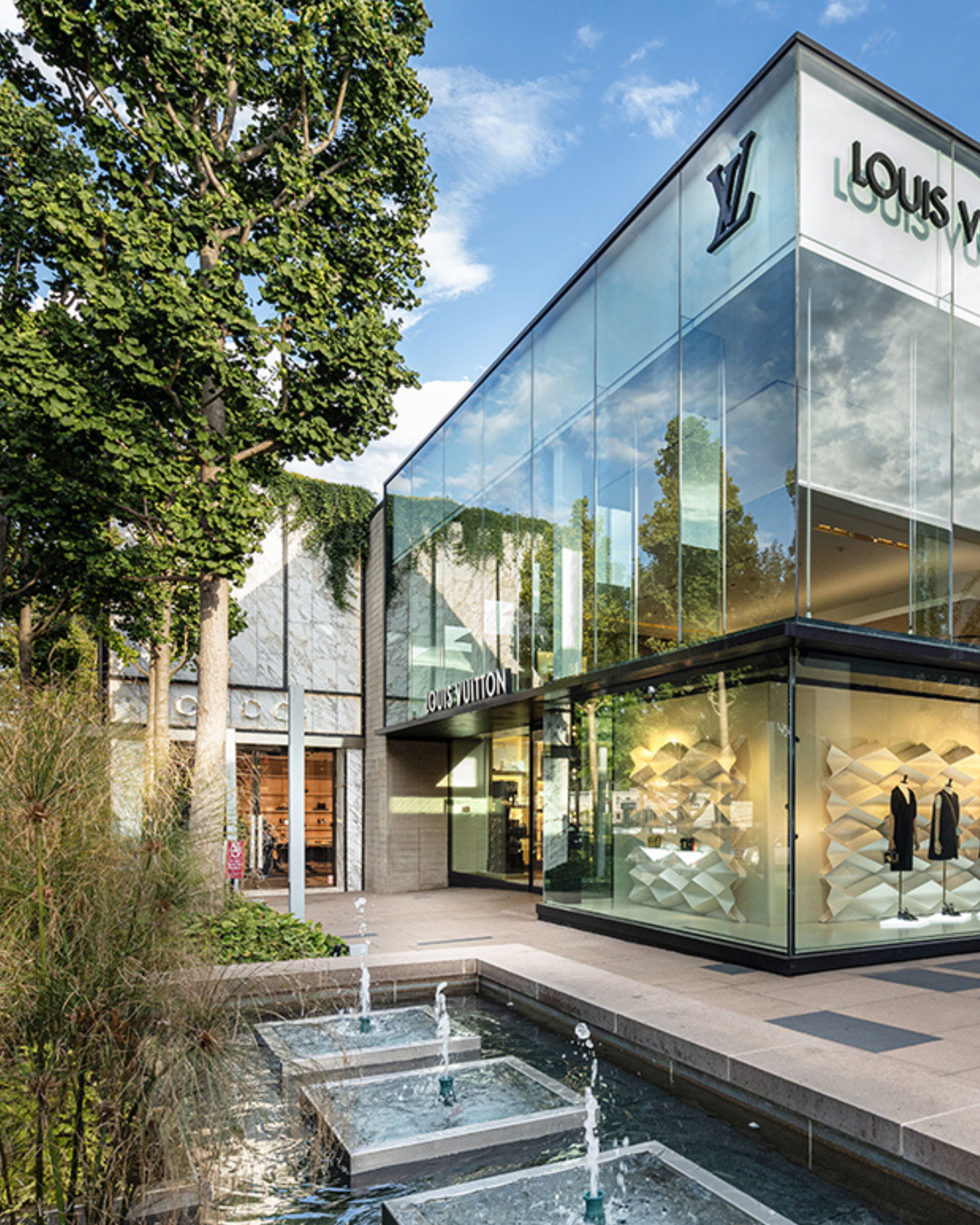 Luxury storefront at the Americana Manhasset in Manhasset, NY, featuring modern glass architecture, landscaped fountains, upscale designer retail, and a polished outdoor shopping environment.