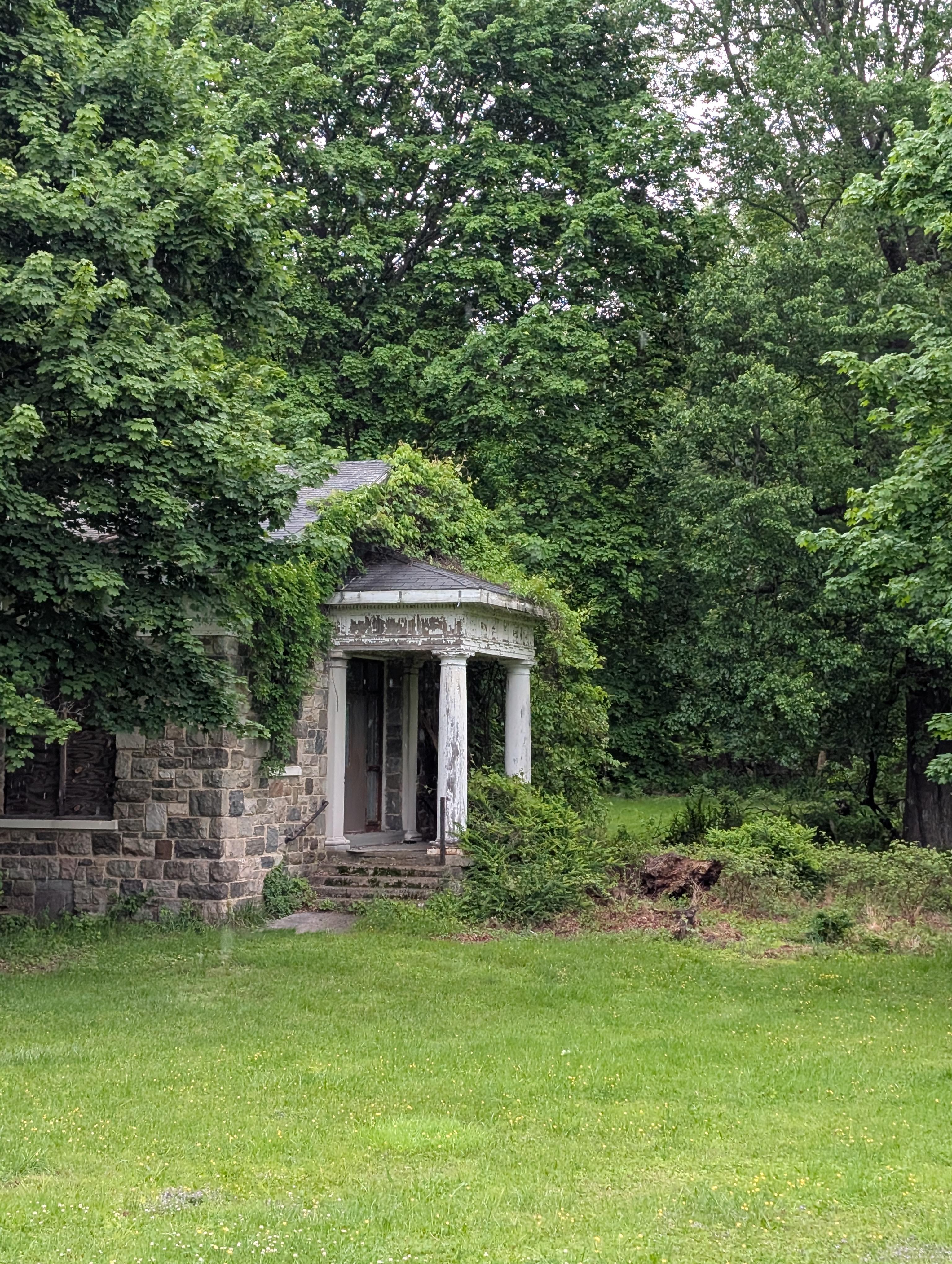 Historic stone building surrounded by dense green woodland and lawn in the Thiells area of Rockland County, New York.