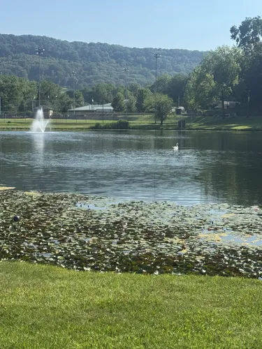 Peck’s Pond Park in West Haverstraw, New York, featuring a peaceful pond with a water fountain, lily pads, green lawns, and wooded Rockland County hills.