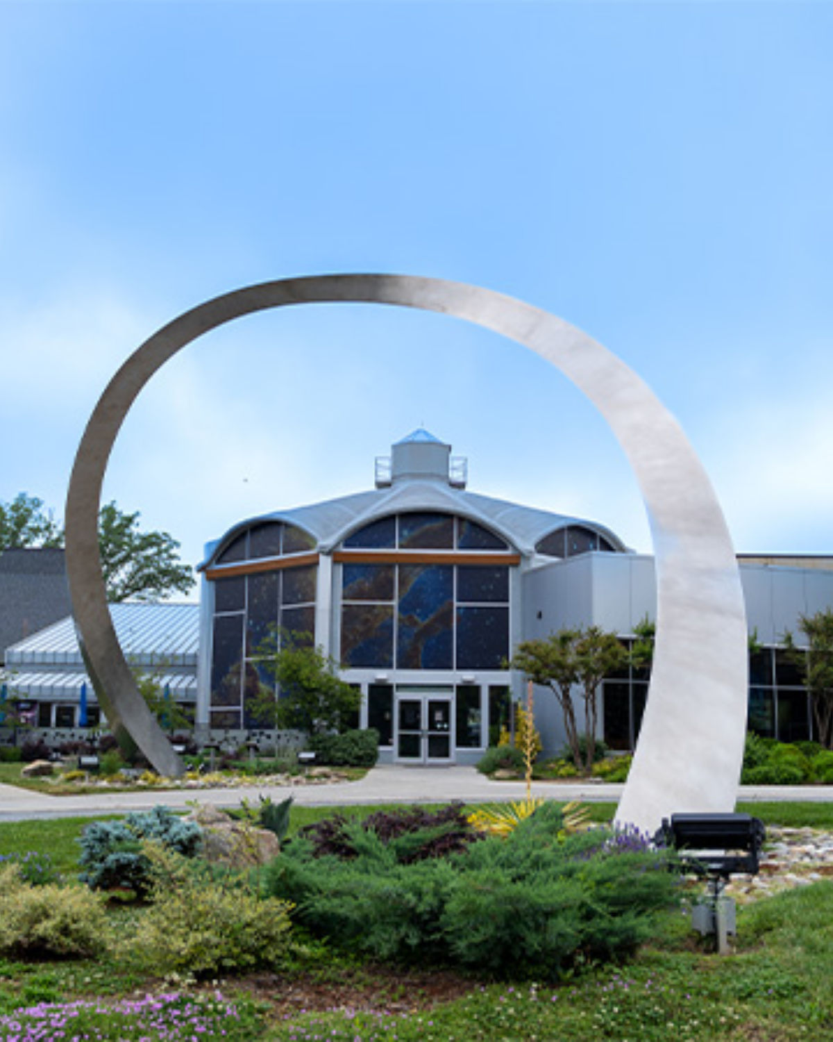 The iconic white arched entrance of the Greensboro Coliseum Complex against a bright blue sky in Greensboro, North Carolina