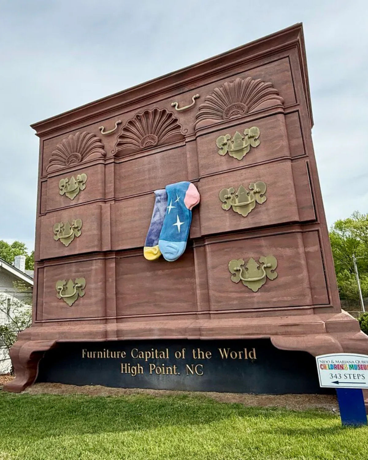 Street-level view of the ŇWorldŐs Largest Chest of DrawersÓ landmark in High Point, North Carolina, showing the towering dresser above a base reading ŇFurniture Capital of the World Đ High Point, NC"