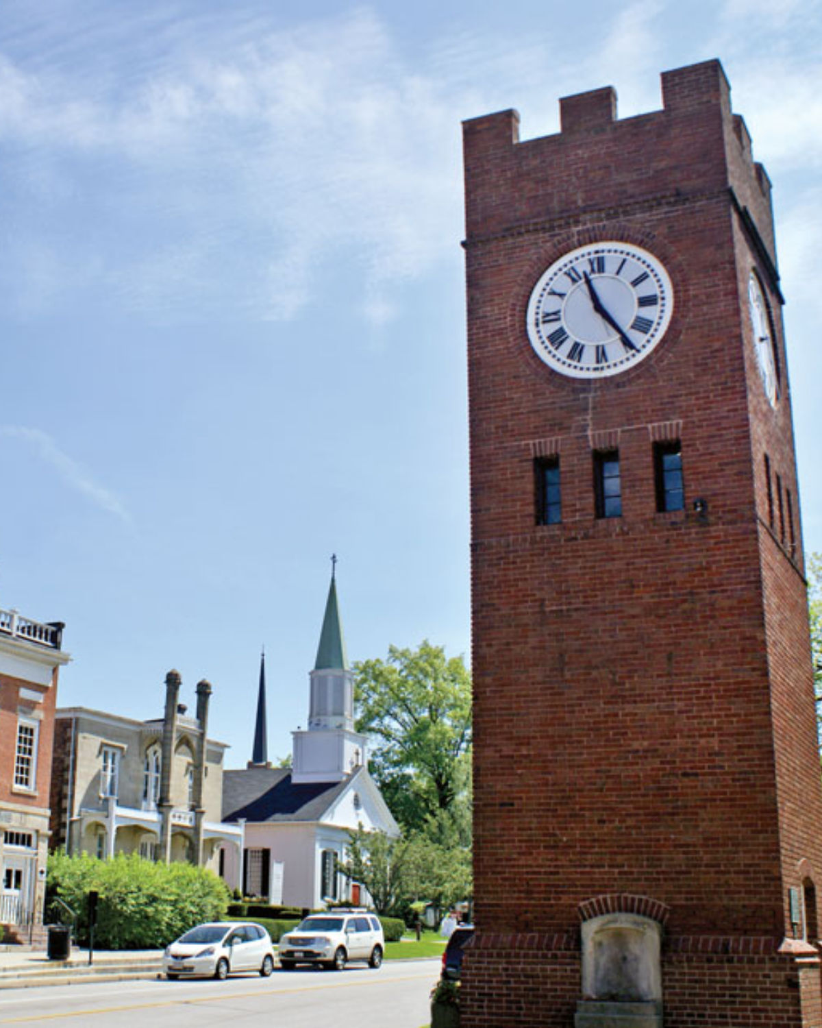 The iconic Hudson Clock Tower rising above historic red brick buildings and church steeples in the preserved village green of downtown Hudson, Ohio