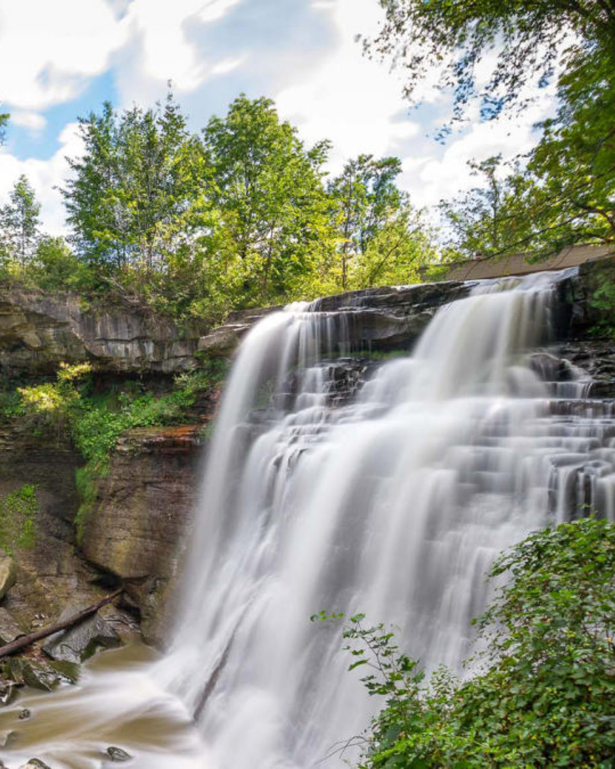 Stunning waterfall cascading over dark rocky ledges surrounded by lush green forest in Twinsburg, Ohio