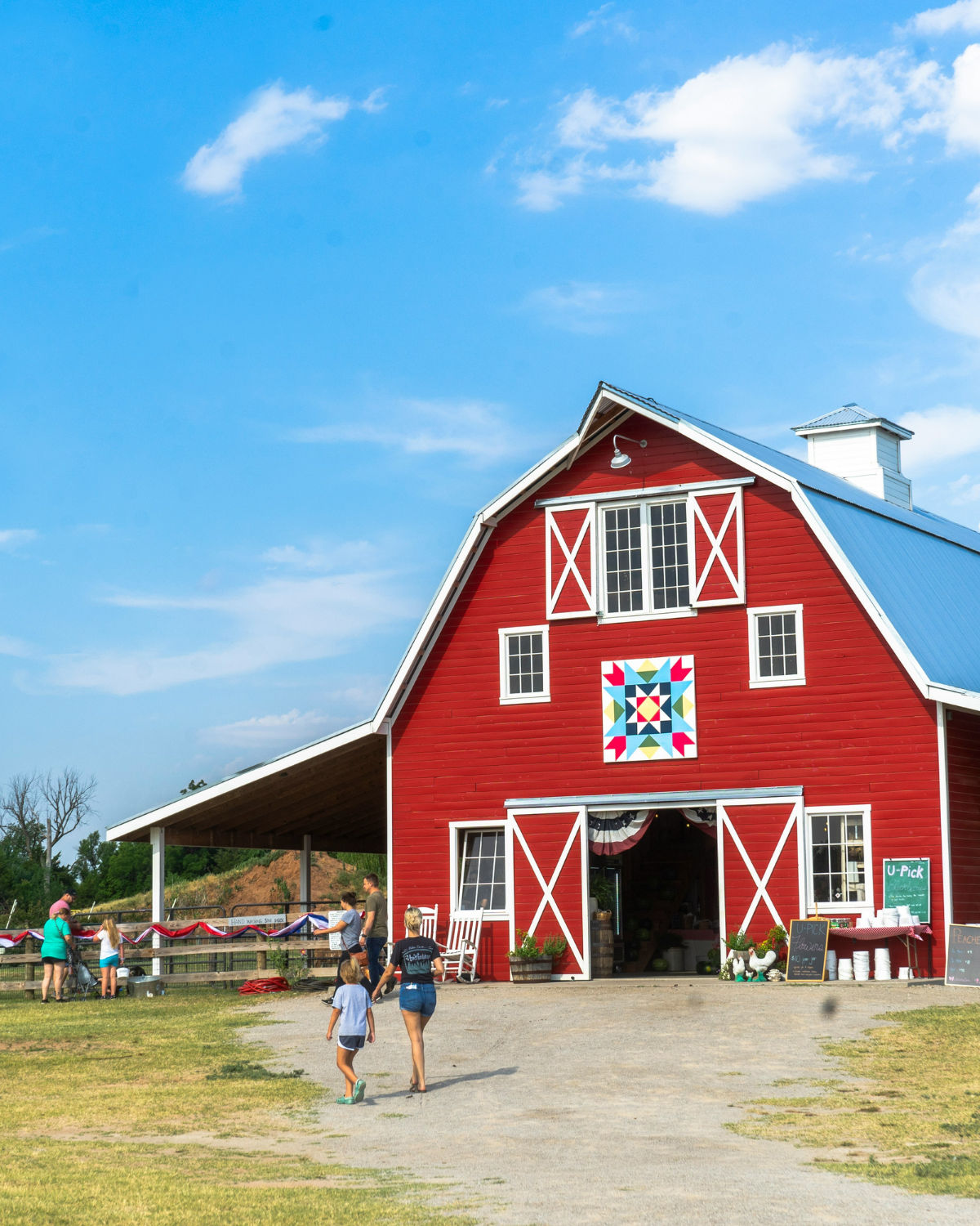 Iconic red barn with a colorful quilt block pattern on the facade under a bright blue sky in rural Oklahoma City, Oklahoma