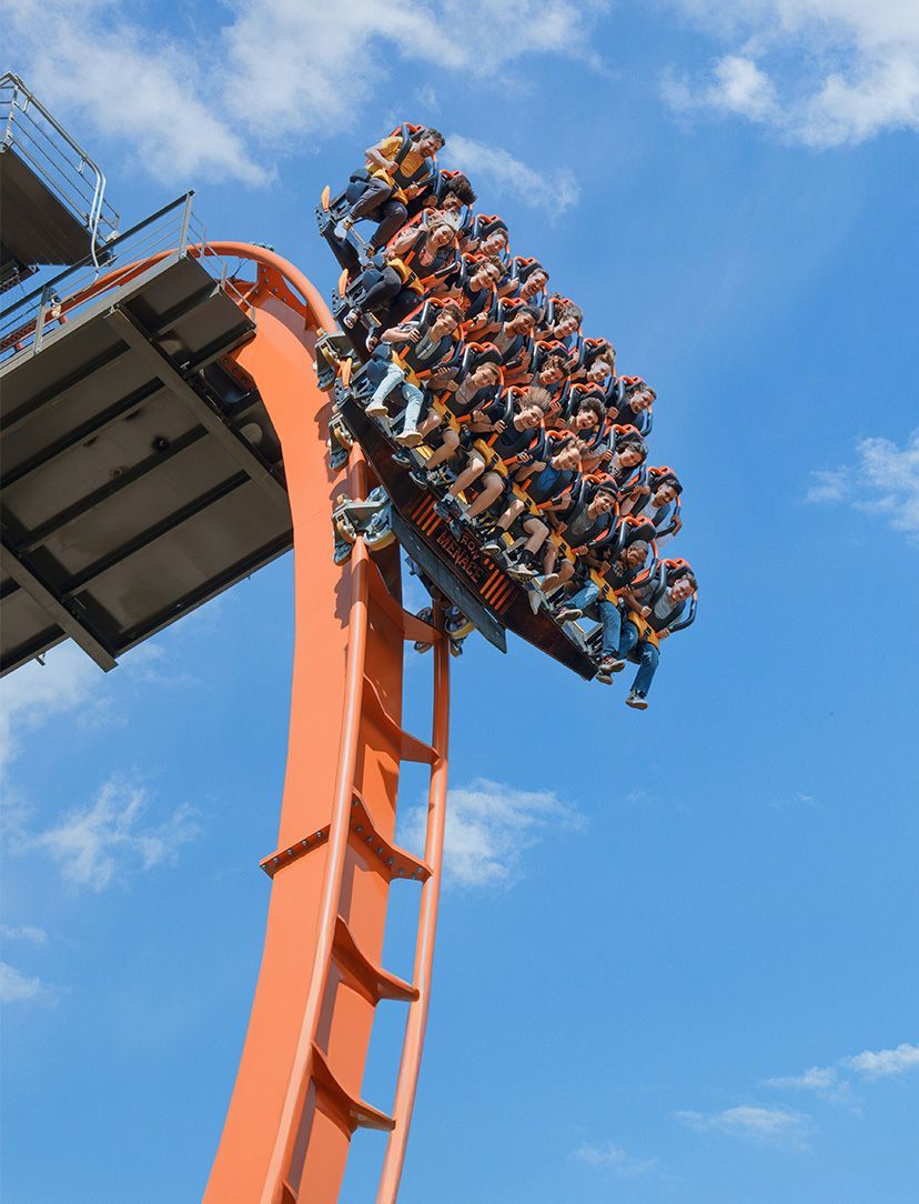 Thrill-seekers ride a roller coaster at Dorney Park & Wildwater Kingdom in Allentown, Pennsylvania. The bright orange coaster twists against a blue sky as riders experience a steep drop, showcasing one of the region’s most popular amusement park attractions.