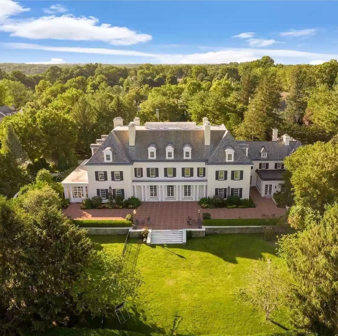 Aerial view of a grand estate in Bryn Mawr, PA featuring a large historic mansion with classic Main Line architecture, symmetrical design, and expansive landscaped grounds surrounded by lush greenery.