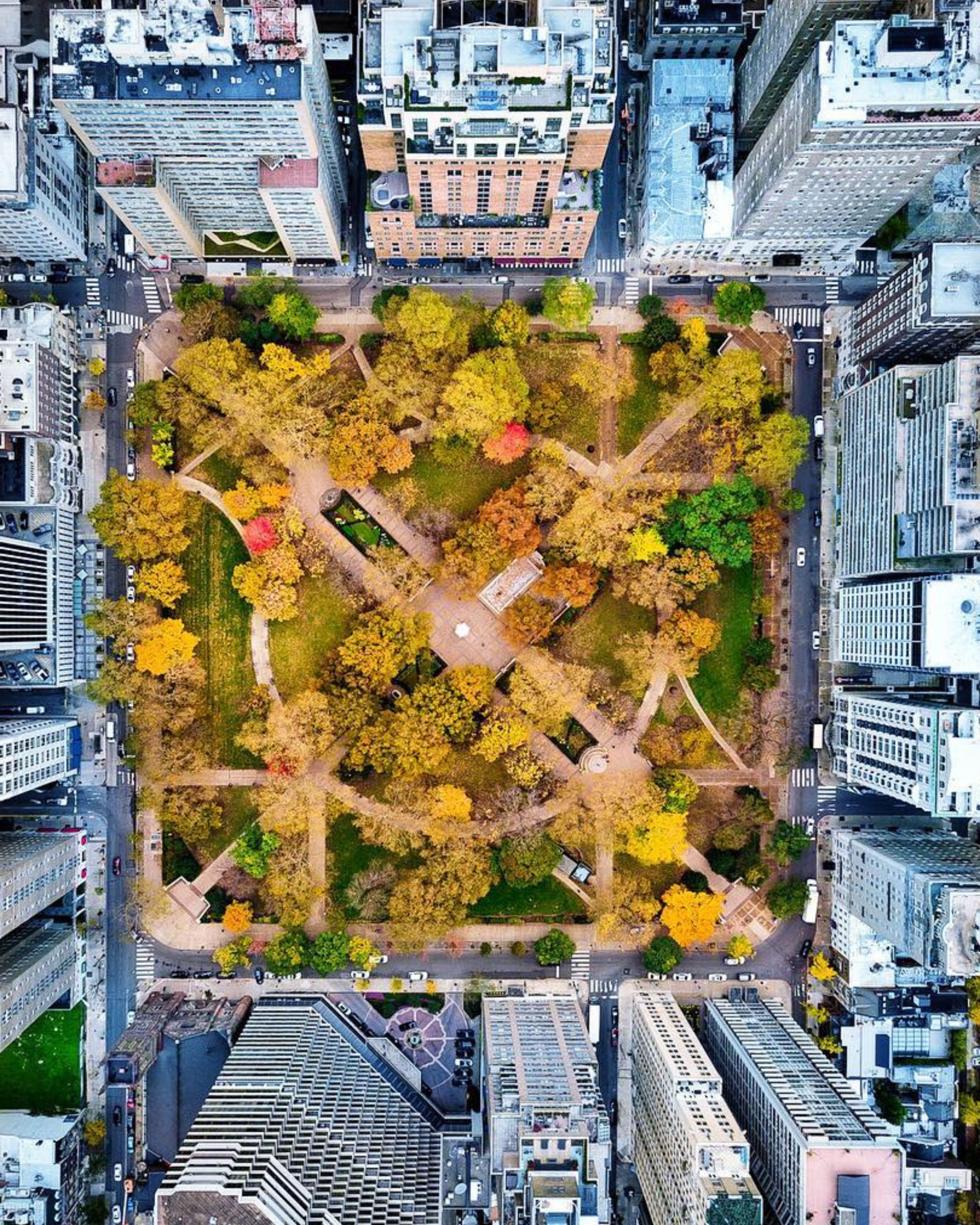 Aerial view of Rittenhouse Square in Philadelphia, Pennsylvania during fall, showcasing the park’s symmetrical walking paths, central plaza, and vibrant autumn foliage surrounded by dense city blocks, high-rise buildings, and streets lined with cars framing the square.