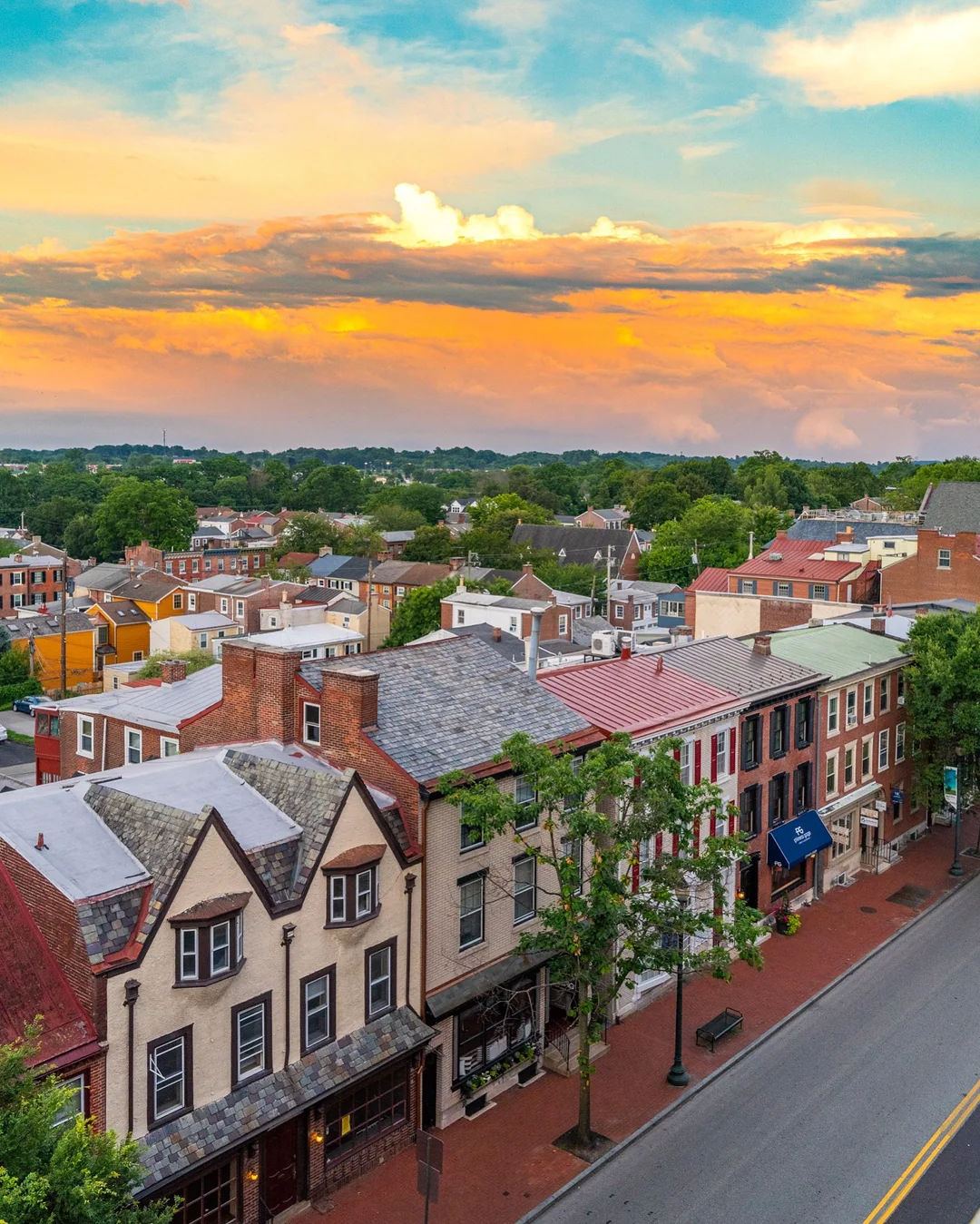 Elevated view of downtown West Chester, Pennsylvania, featuring historic brick storefronts, colorful architecture, and the walkable streets of the town's vibrant historic district at sunset.