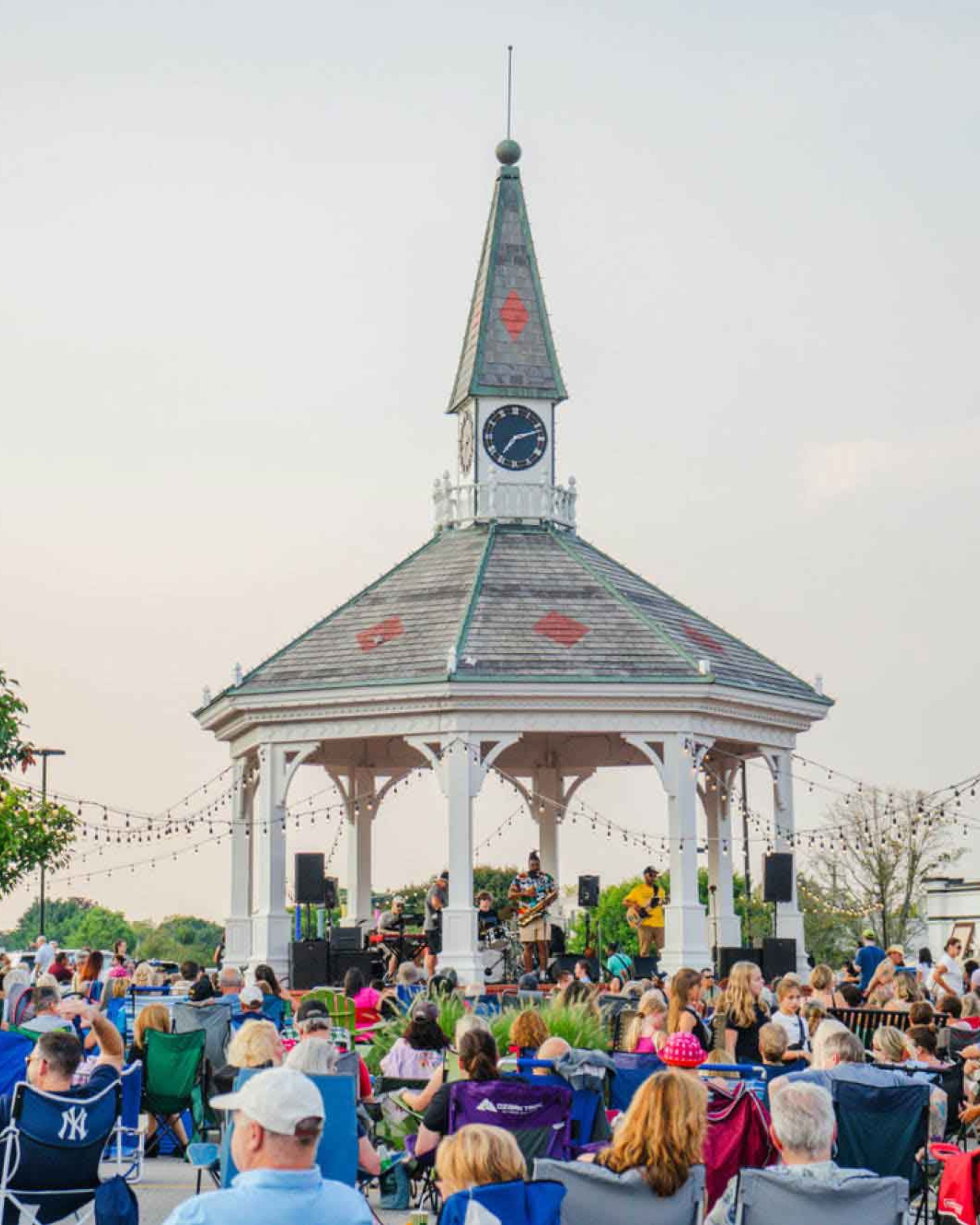 Crowds gathered at the historic gazebo in Pawtuxet Village, Cranston, Rhode Island, enjoying a live outdoor concert and community event on a summer evening.
