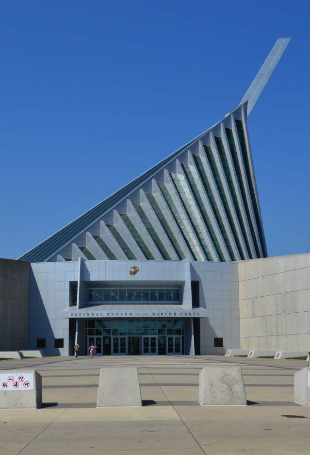 Front entrance of the National Museum of the Marine Corps near Dumfries, Virginia, featuring the museum's iconic angular architecture, expansive entrance plaza, and modern glass-and-steel design beneath a clear blue sky.