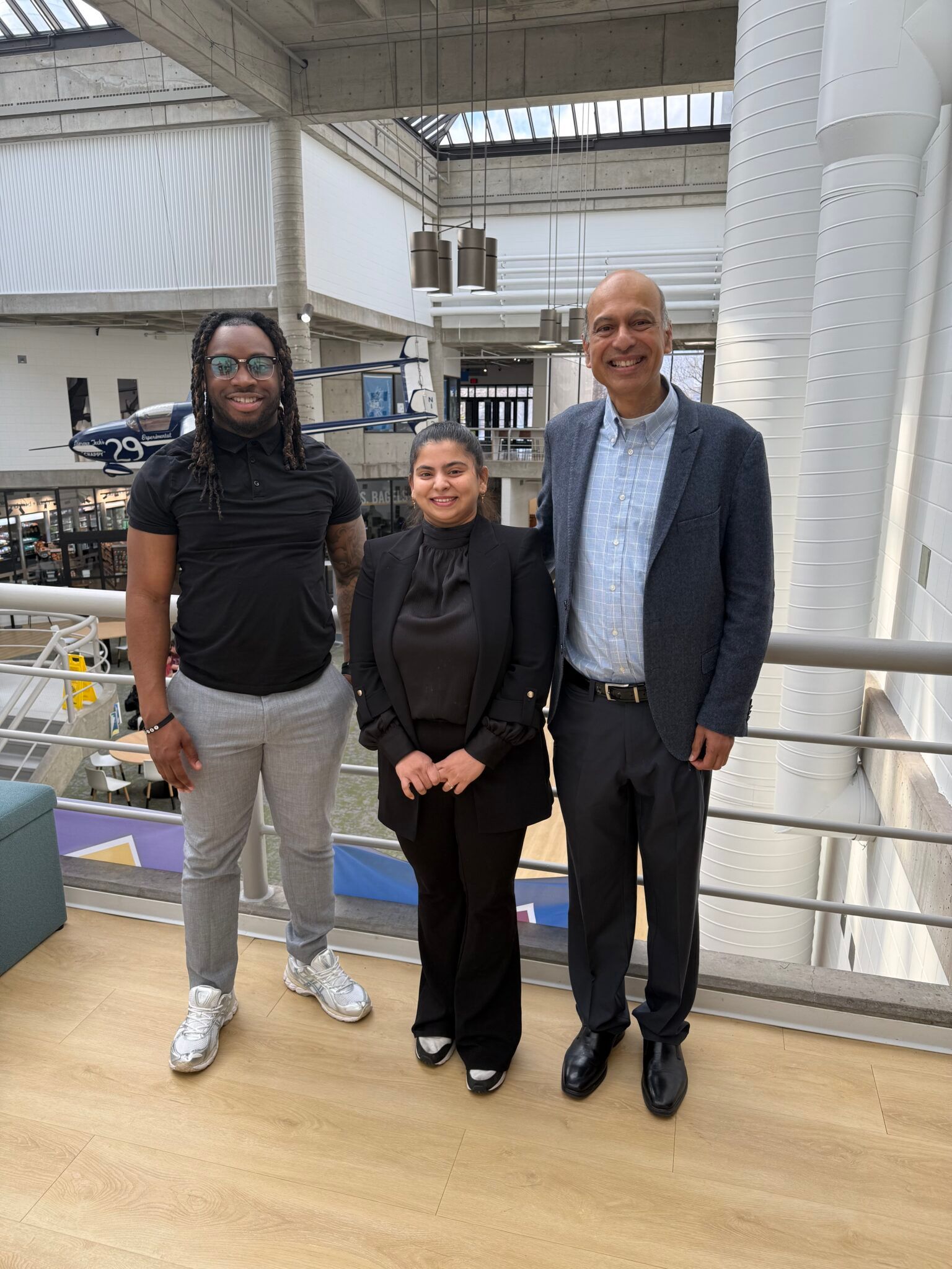 Students Uzma Sayyad and Nicholas Okoro stand next to Adjunct Professor Arun DeSouza