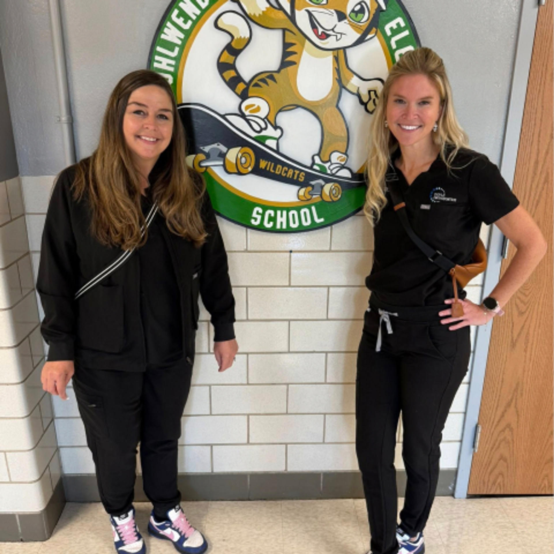 dr doyle and employee posing in front of school mascot sign