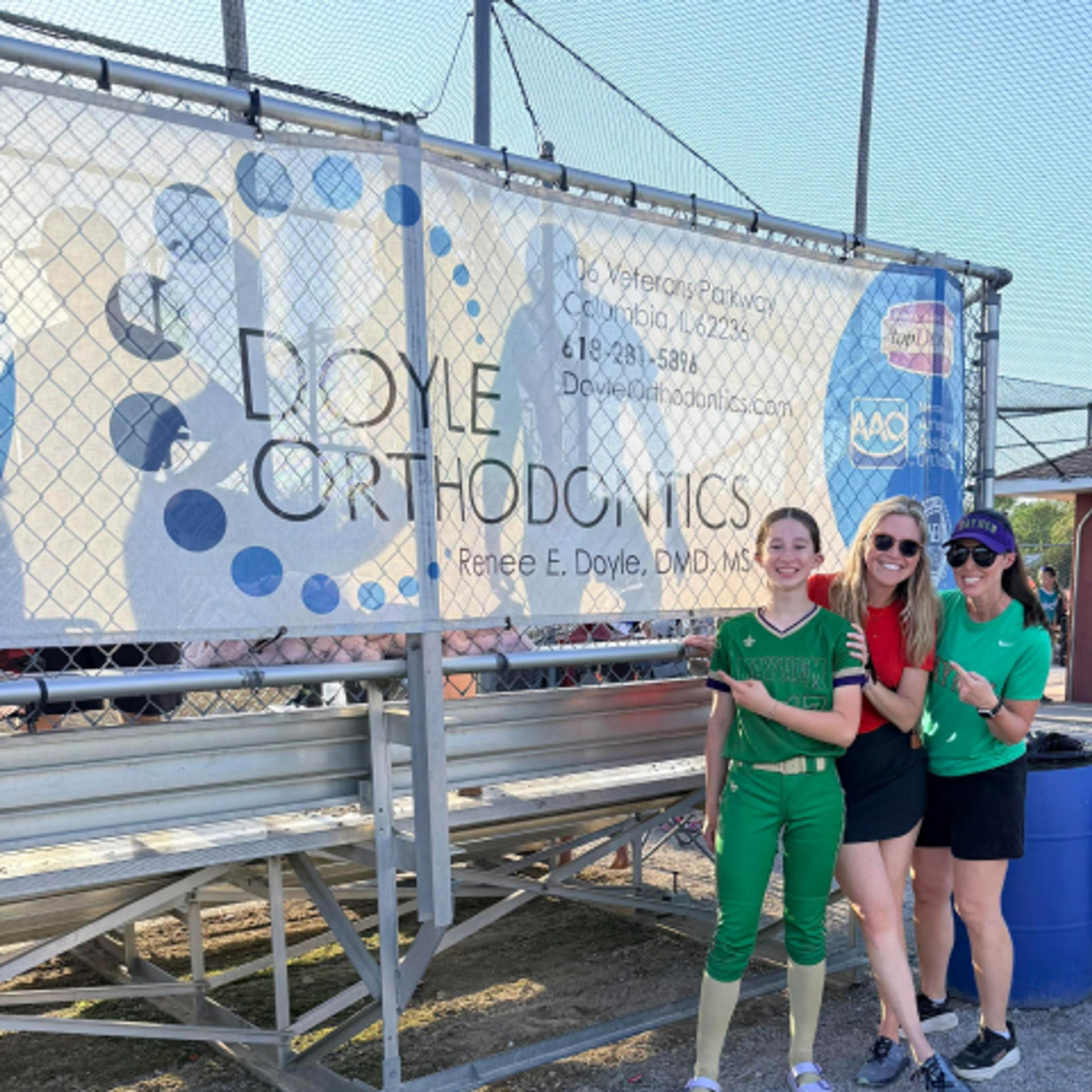 dr coyle and two others posing in front of Doyle Orthodontics sponsorship banner