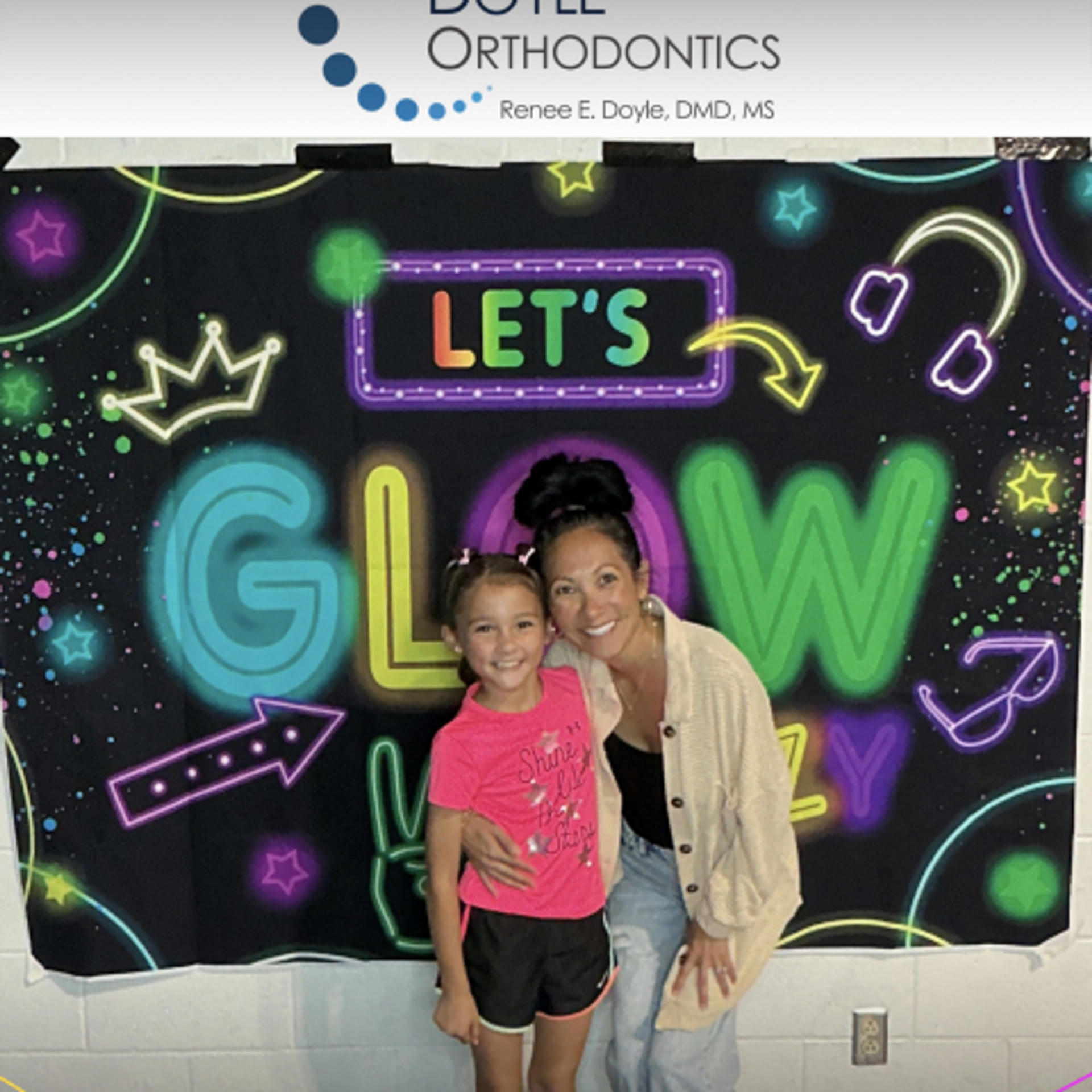 mom and daughter posing in front of Let's Glow banner