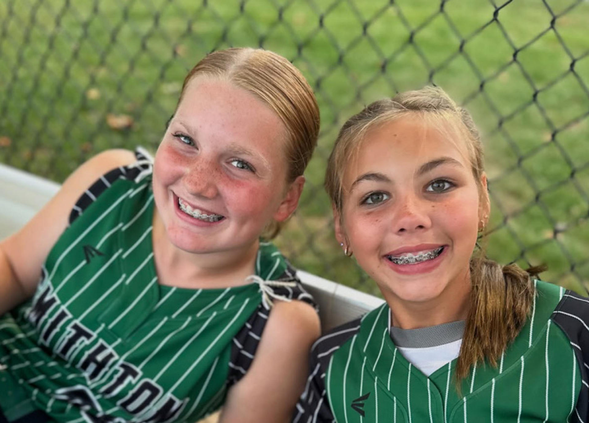 two teenage girls with braces in sports uniforms