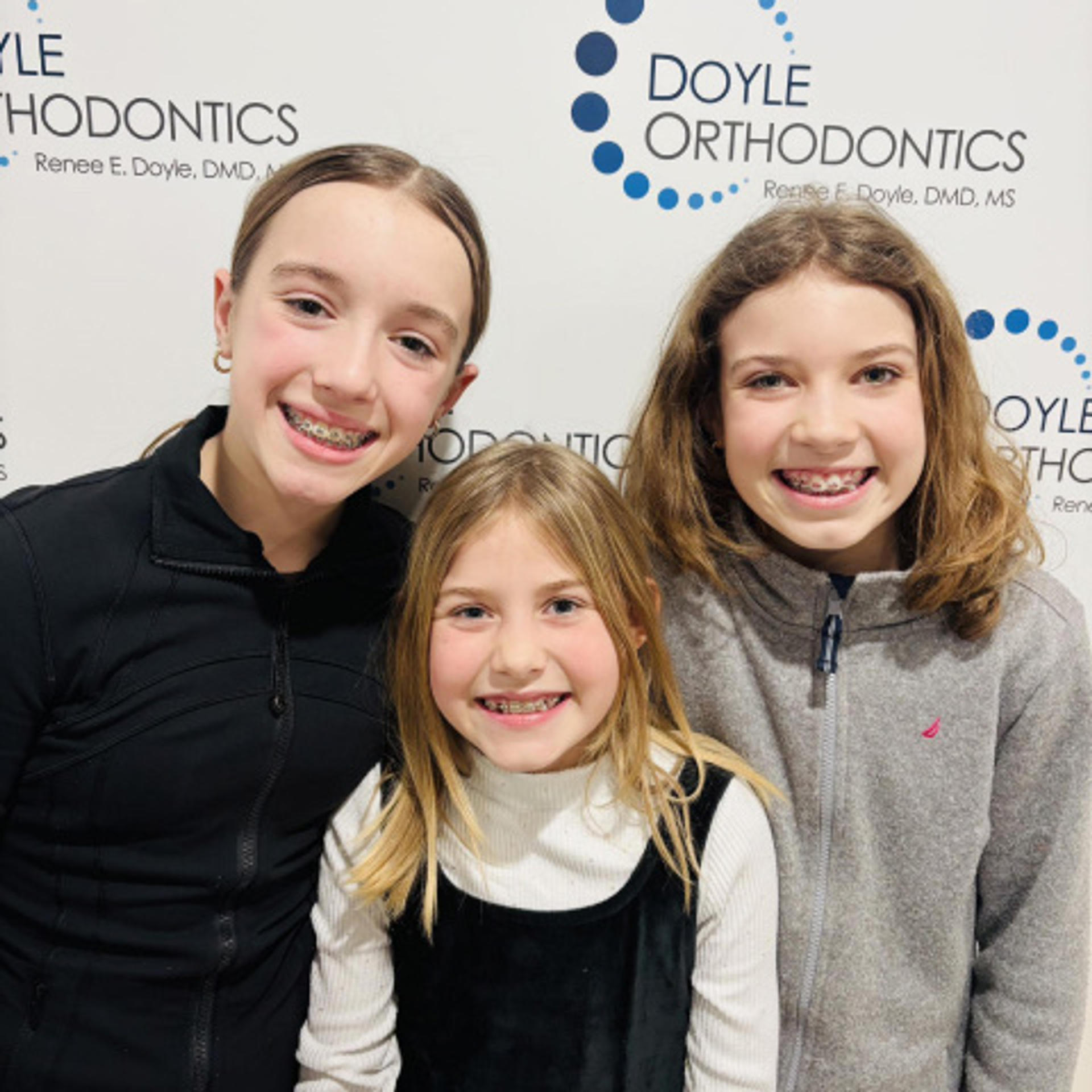 three smiling kids in braces