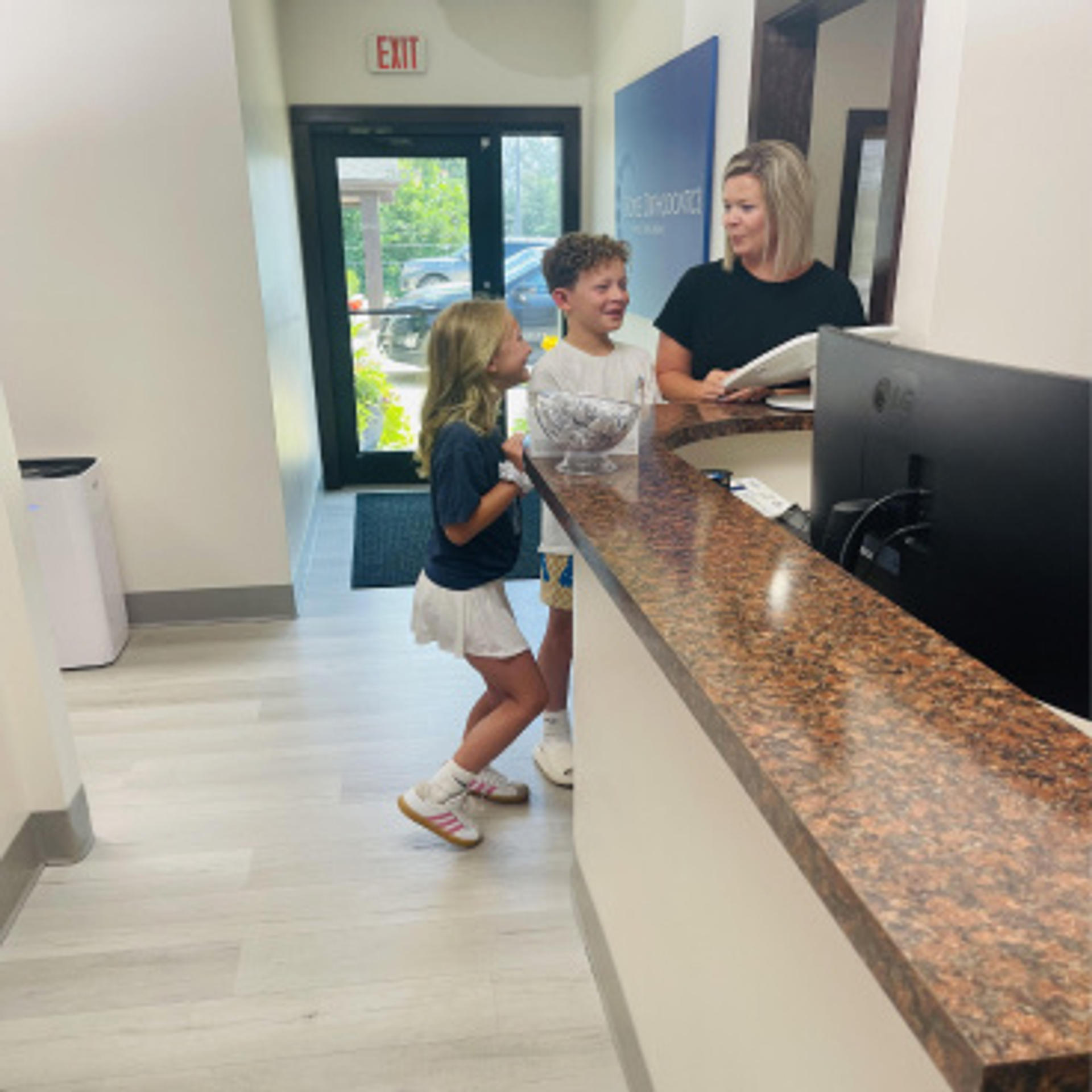 two kids and an adult at the front desk of doyle orthodontics