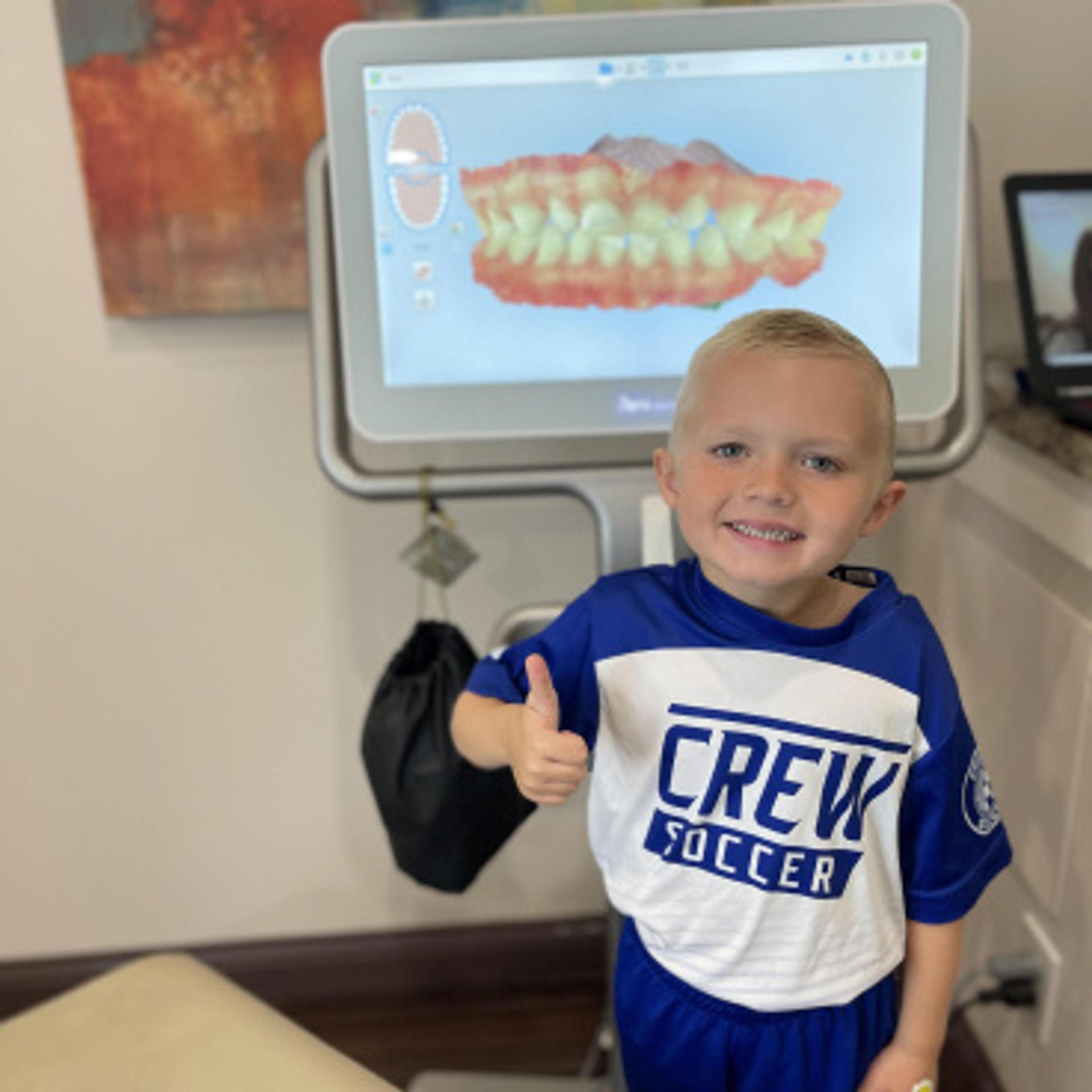 a smiling child giving the thumbs up in front of an itero machine