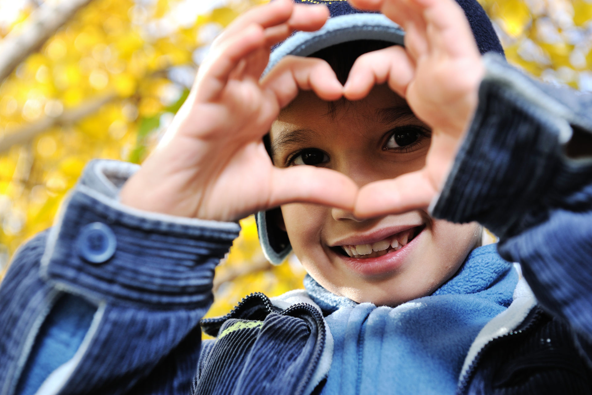 young child making a heart with his hands