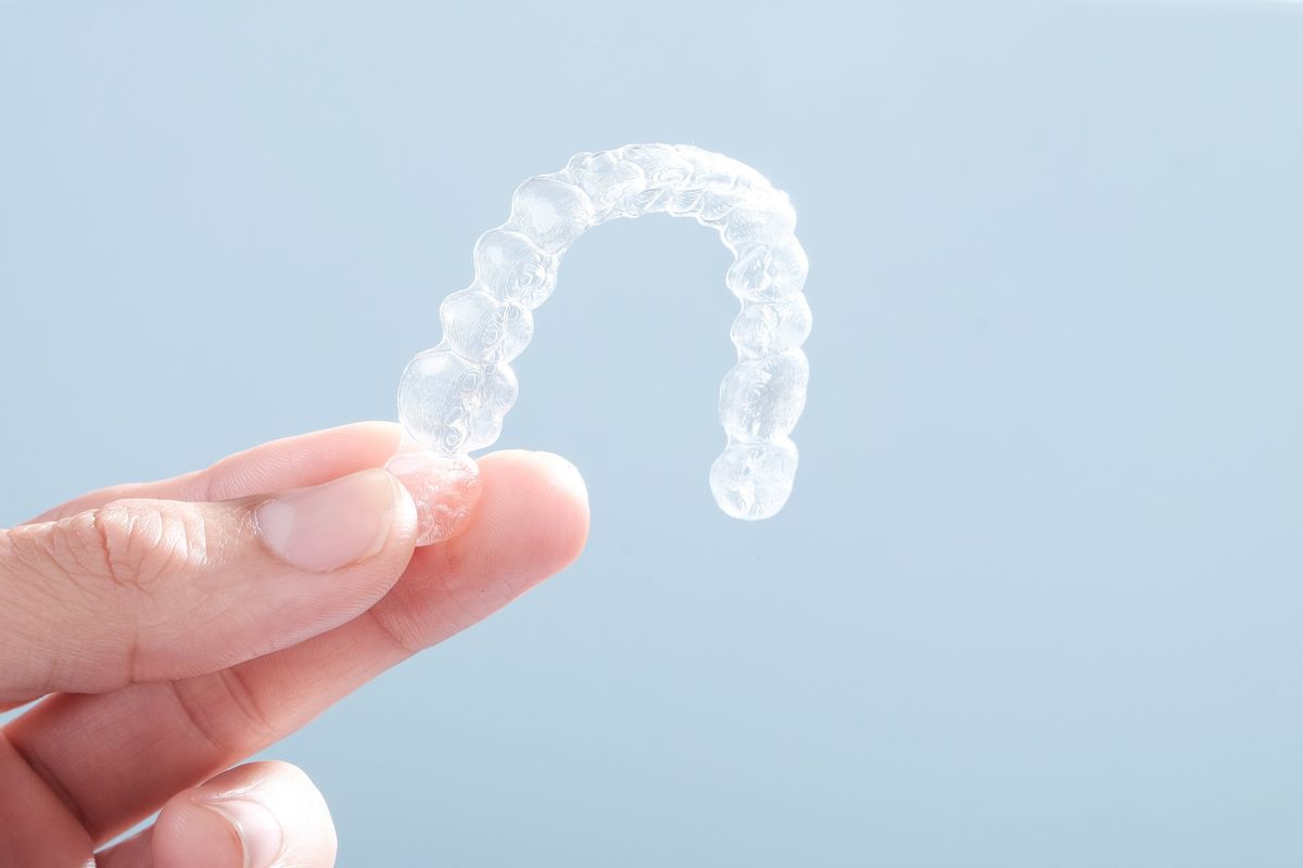A hand holding a clear orthodontic aligner