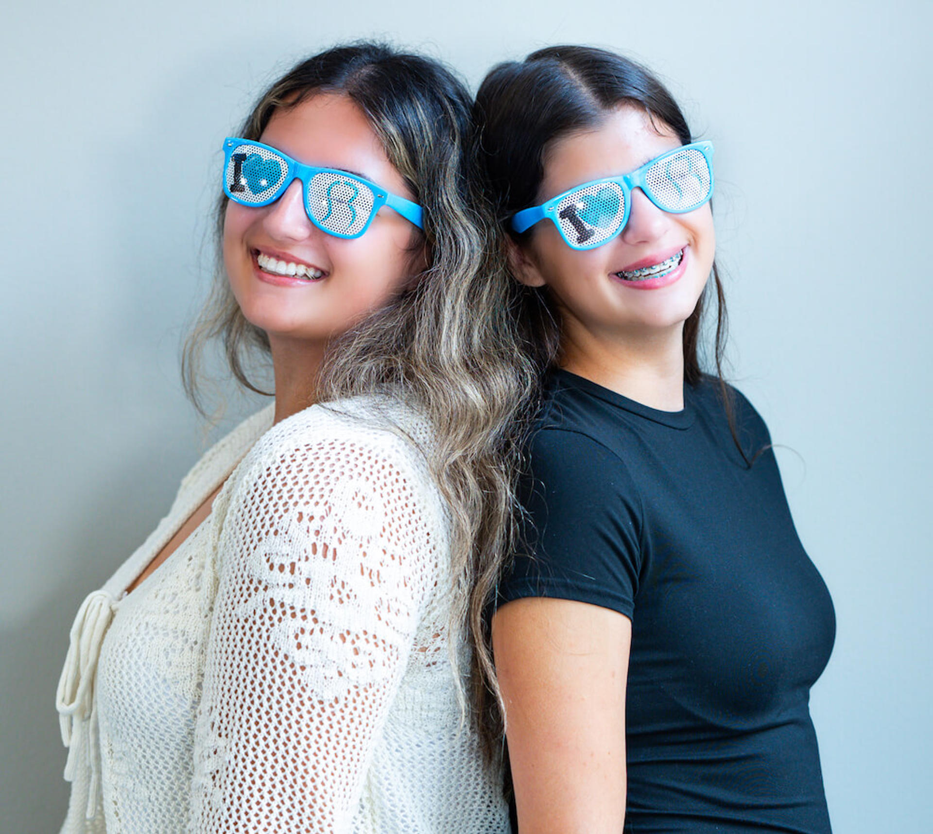 two girls back to back with reynolds orthodontics branded glasses