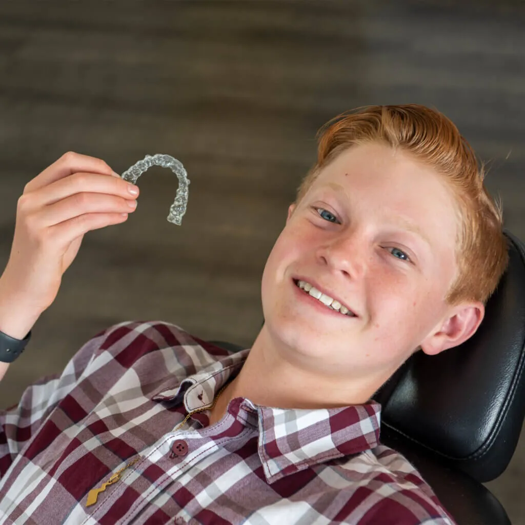 boy holding aligners smiling