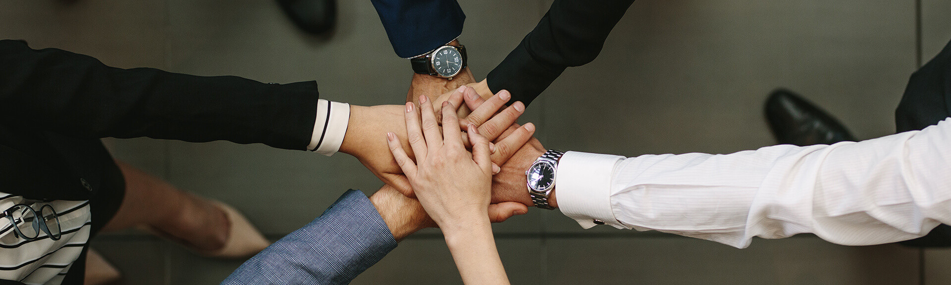 Team members stacking their hands together in a show of unity.