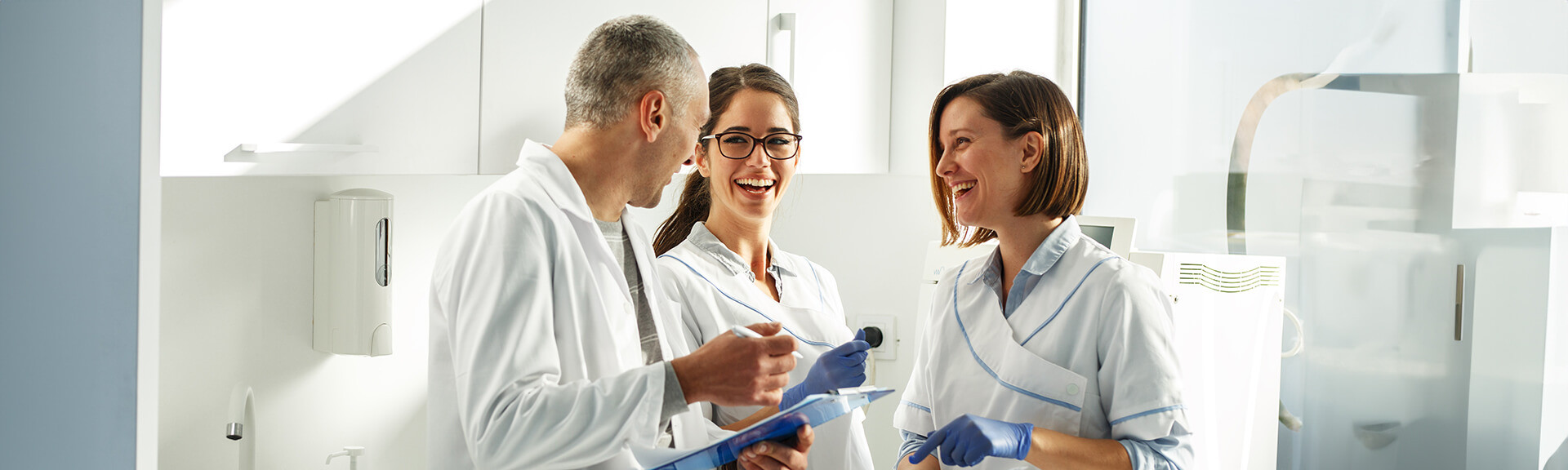 Three orthodontic team members reviewing patient charts together in a clinic.