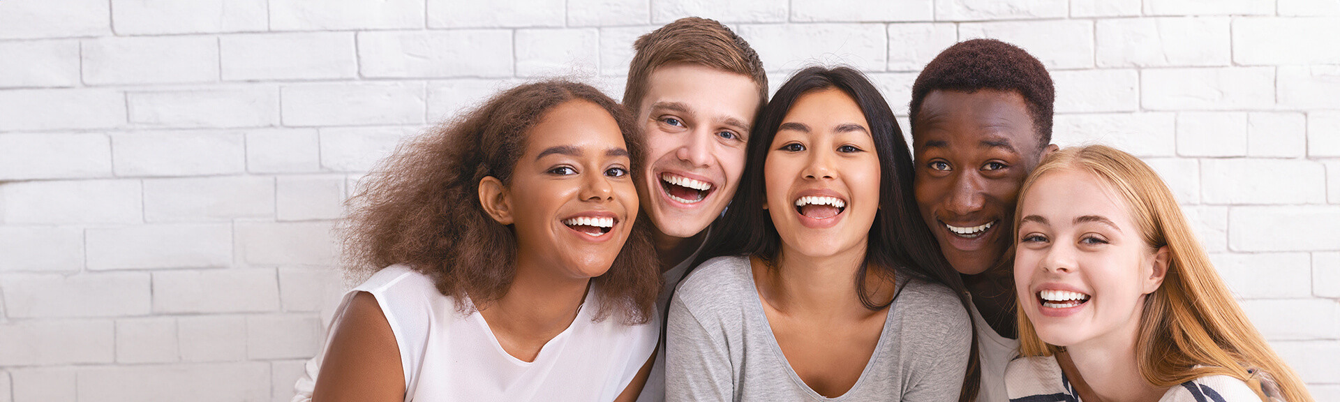 Portrait of happy multiethnic young friends over white wall background