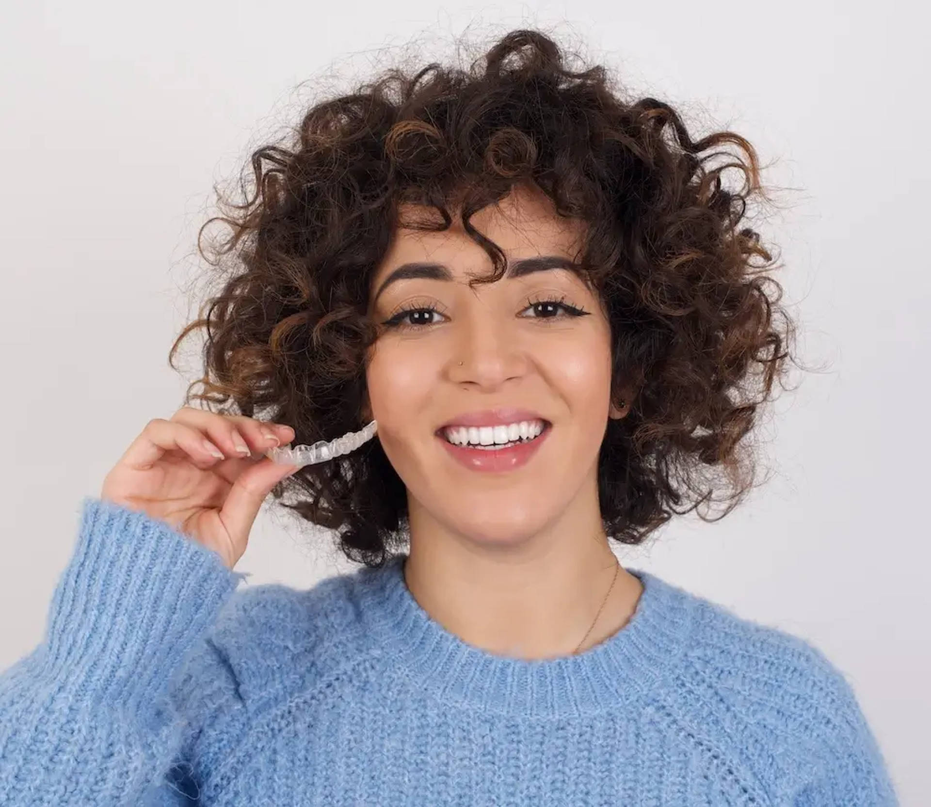 smiling young woman holding aligners