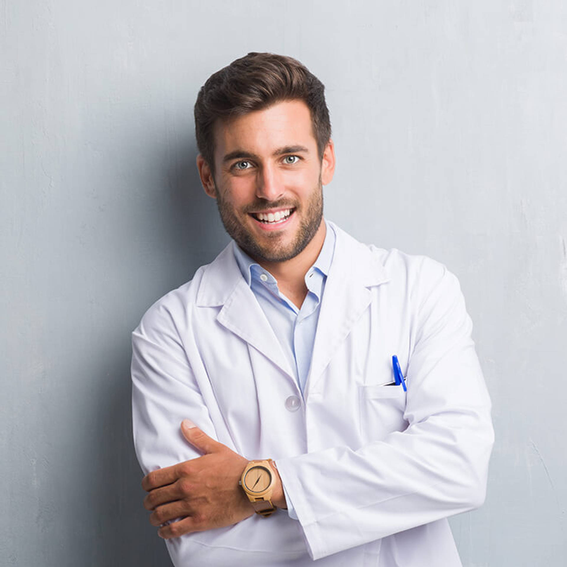 Handsome young professional man over grey grunge wall wearing white coat happy face smiling with crossed arms looking at the camera.