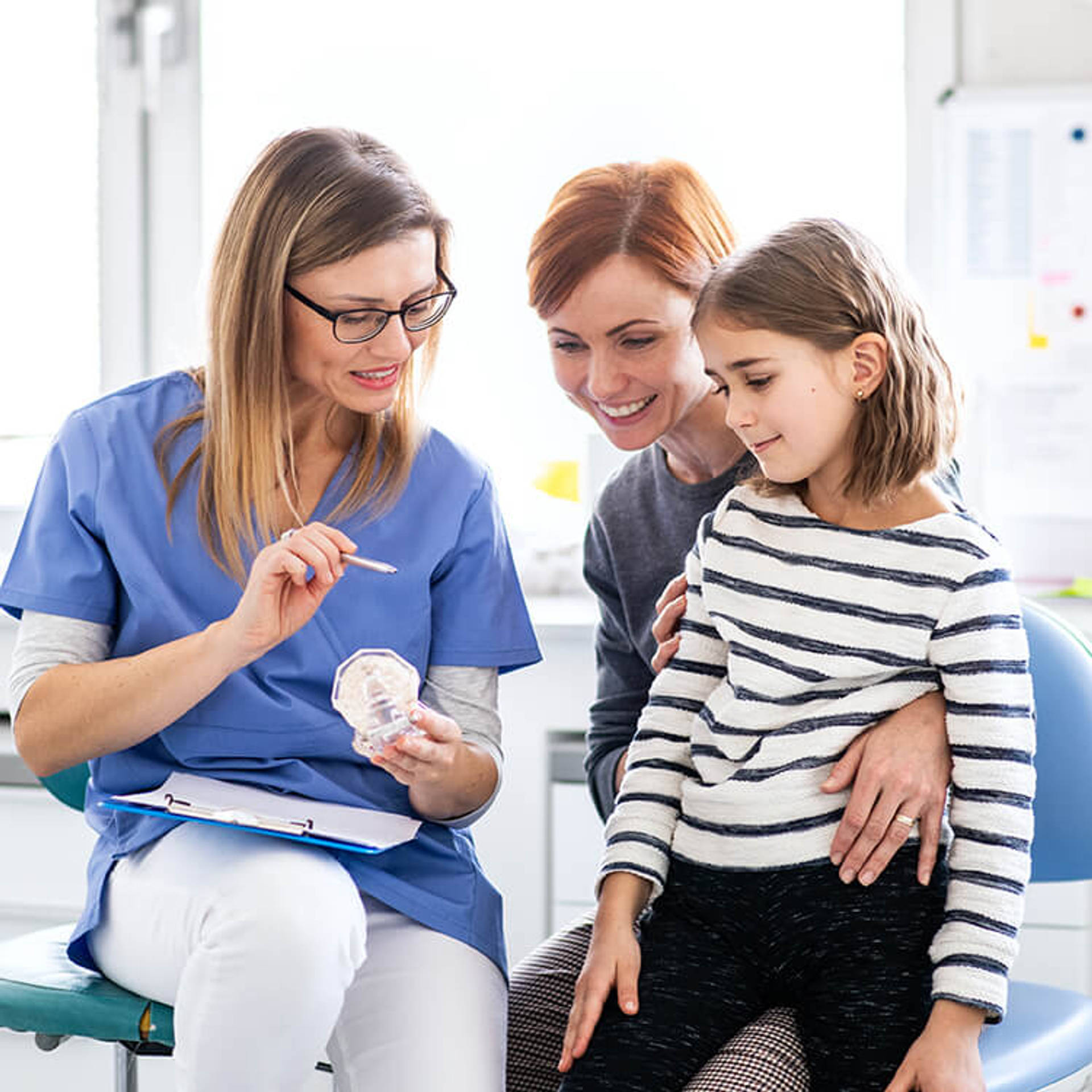 A small girl, mother and dentist in surgery, dental checkup.