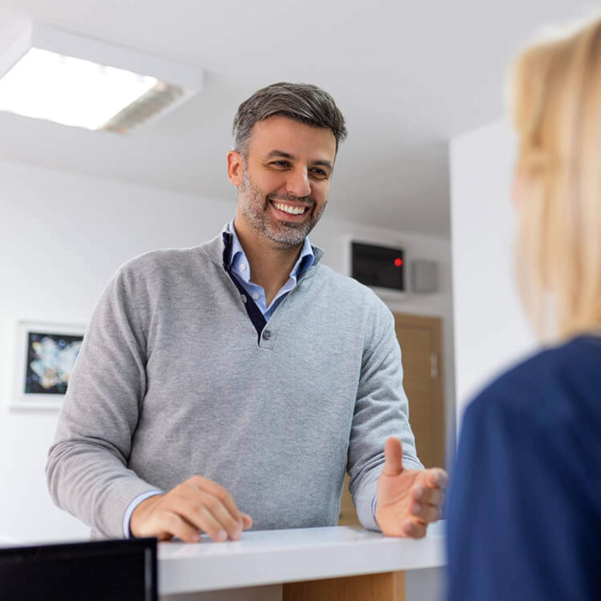 Man making an appointment with medical staffs at reception desk in hospital.